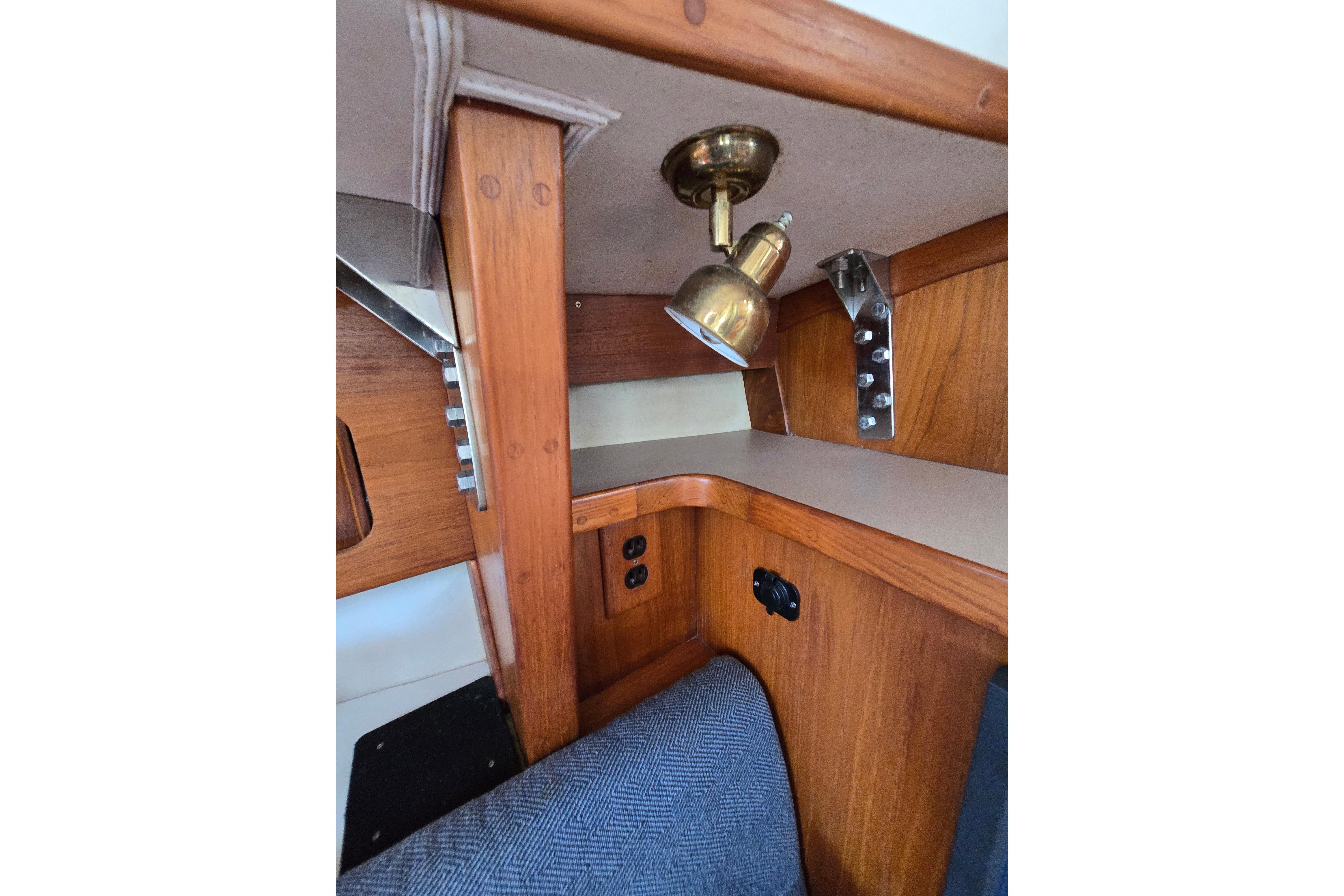 Interior of 1993 Caliber 35 sailboat with wooden cabinetry and brass light fixture.
