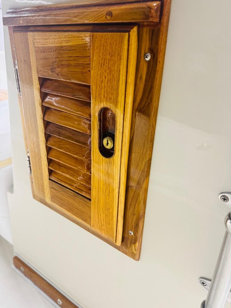 A wooden locker with a louvered door and lock on a boat.