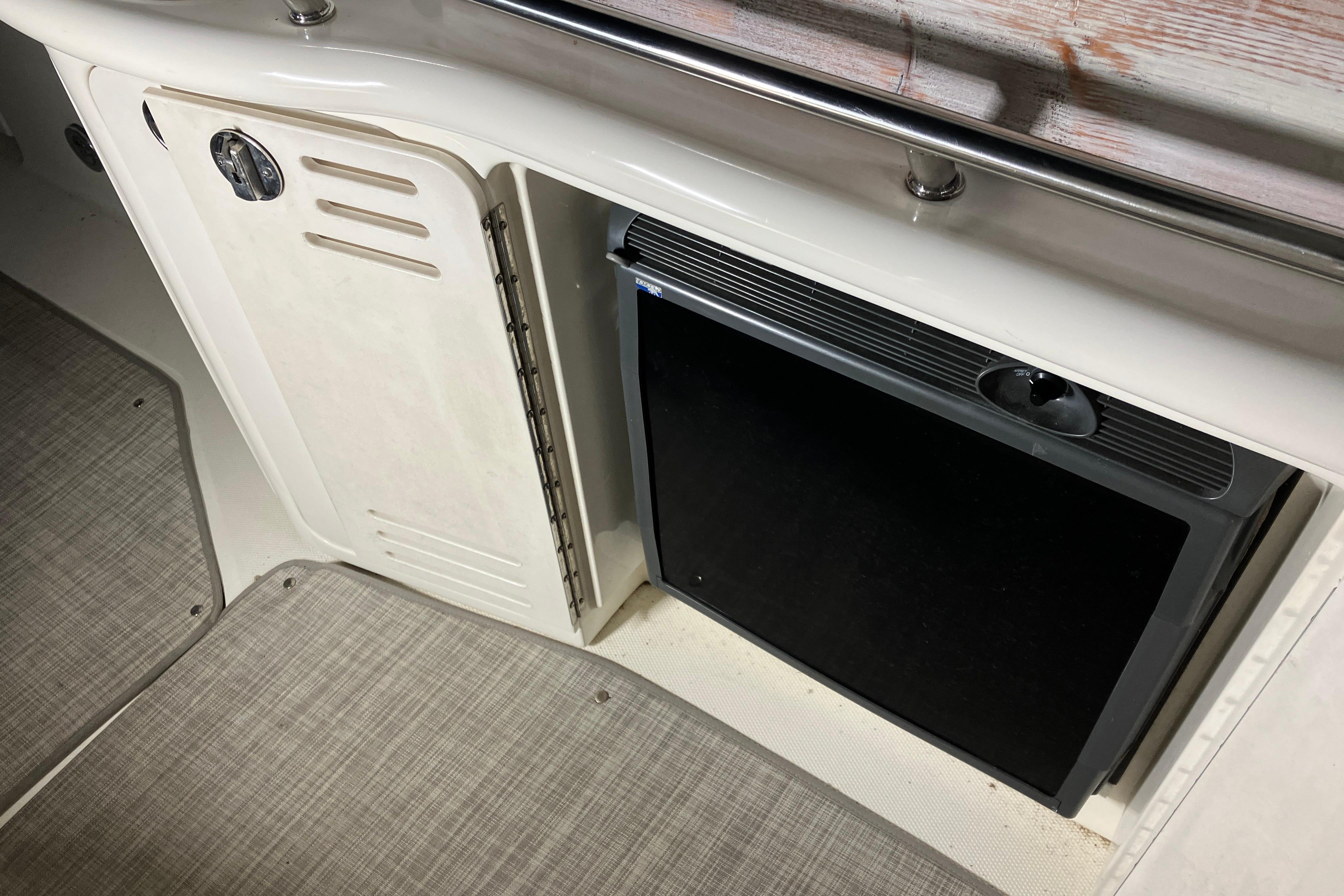 2002 Sea Ray 410 Sundancer interior with storage compartment and mini fridge.