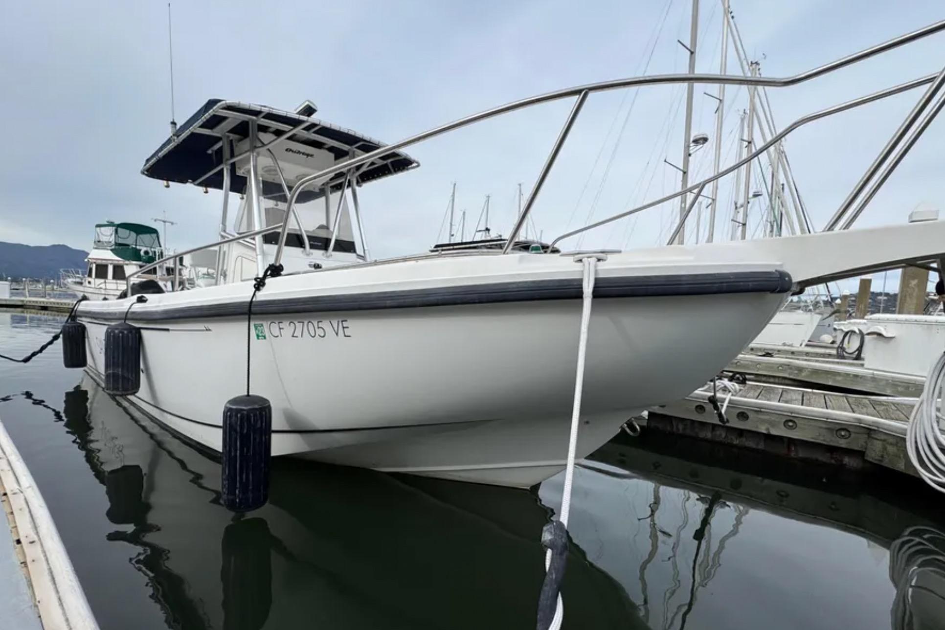 2001 Boston Whaler 26 Outrage boat docked at marina, side view.