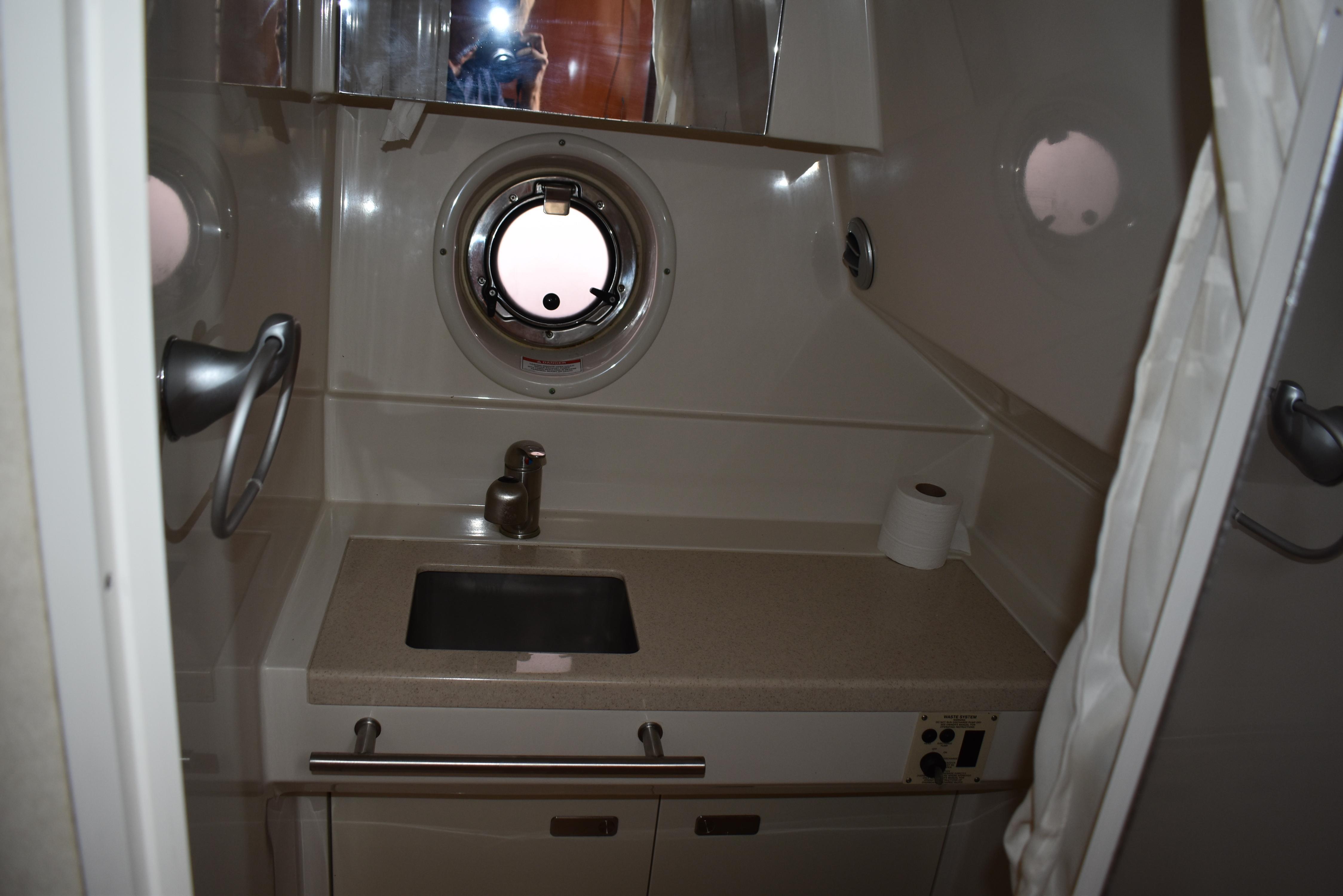 Bathroom interior of 2011 Sea Ray 310 Sundancer yacht with sink and porthole.