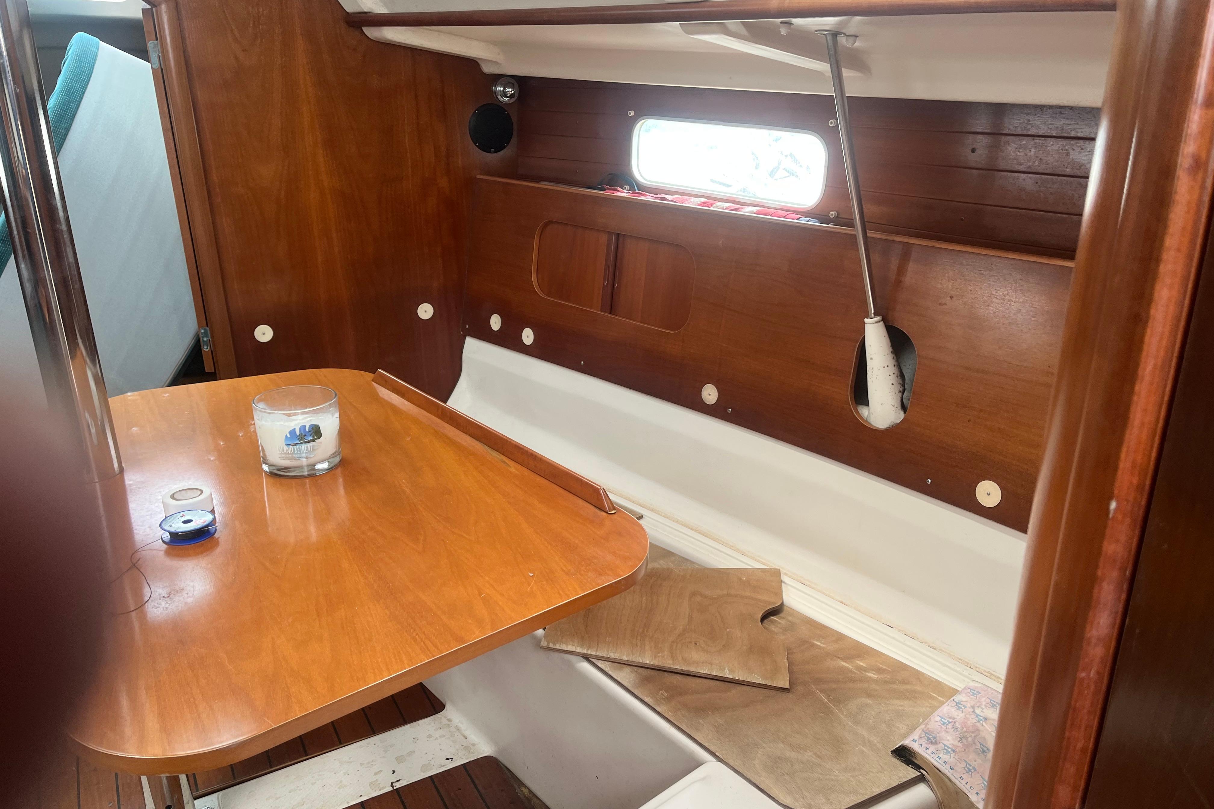 Interior of 1999 Benneteau 321 Oceanis sailboat with wooden table and seating area.
