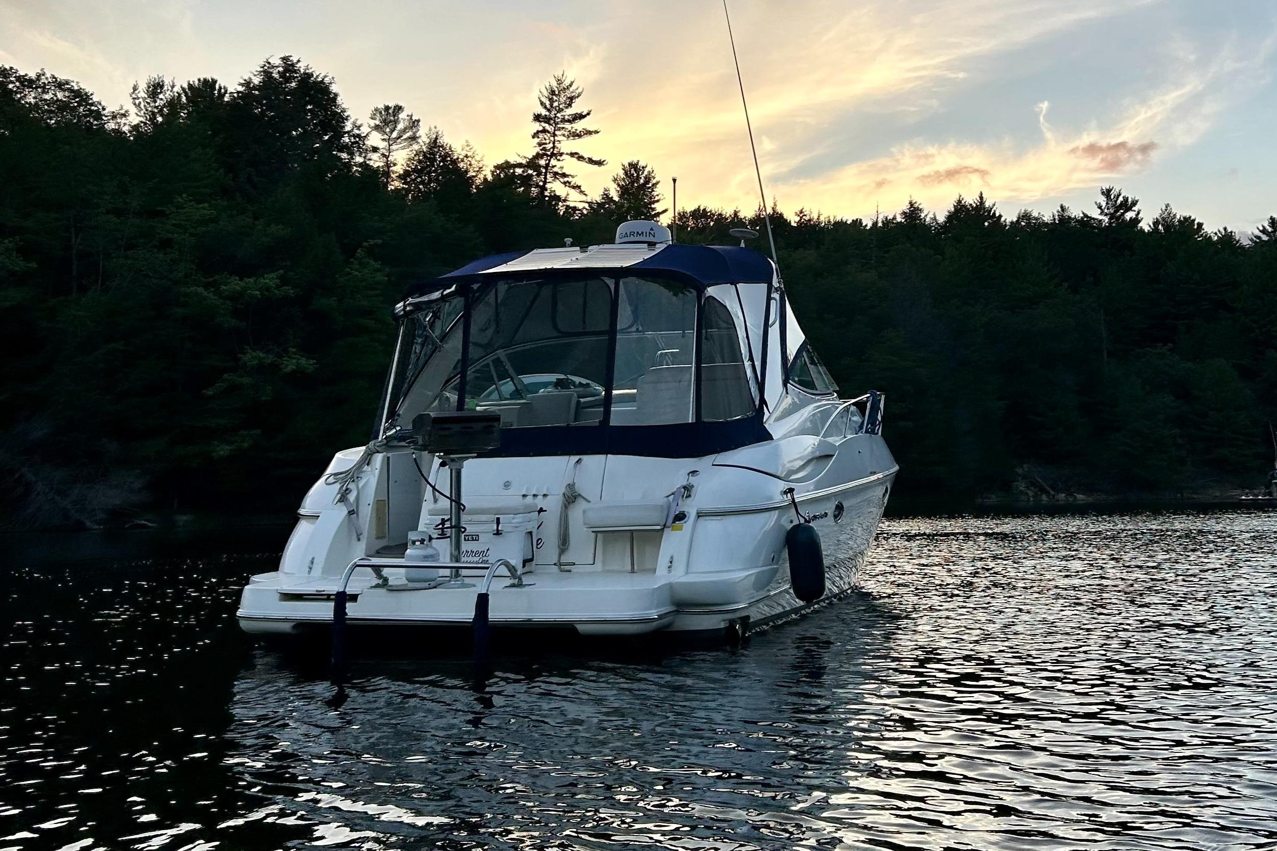 2003 Cruisers Yachts 3470 Express on a tranquil lake at sunset.