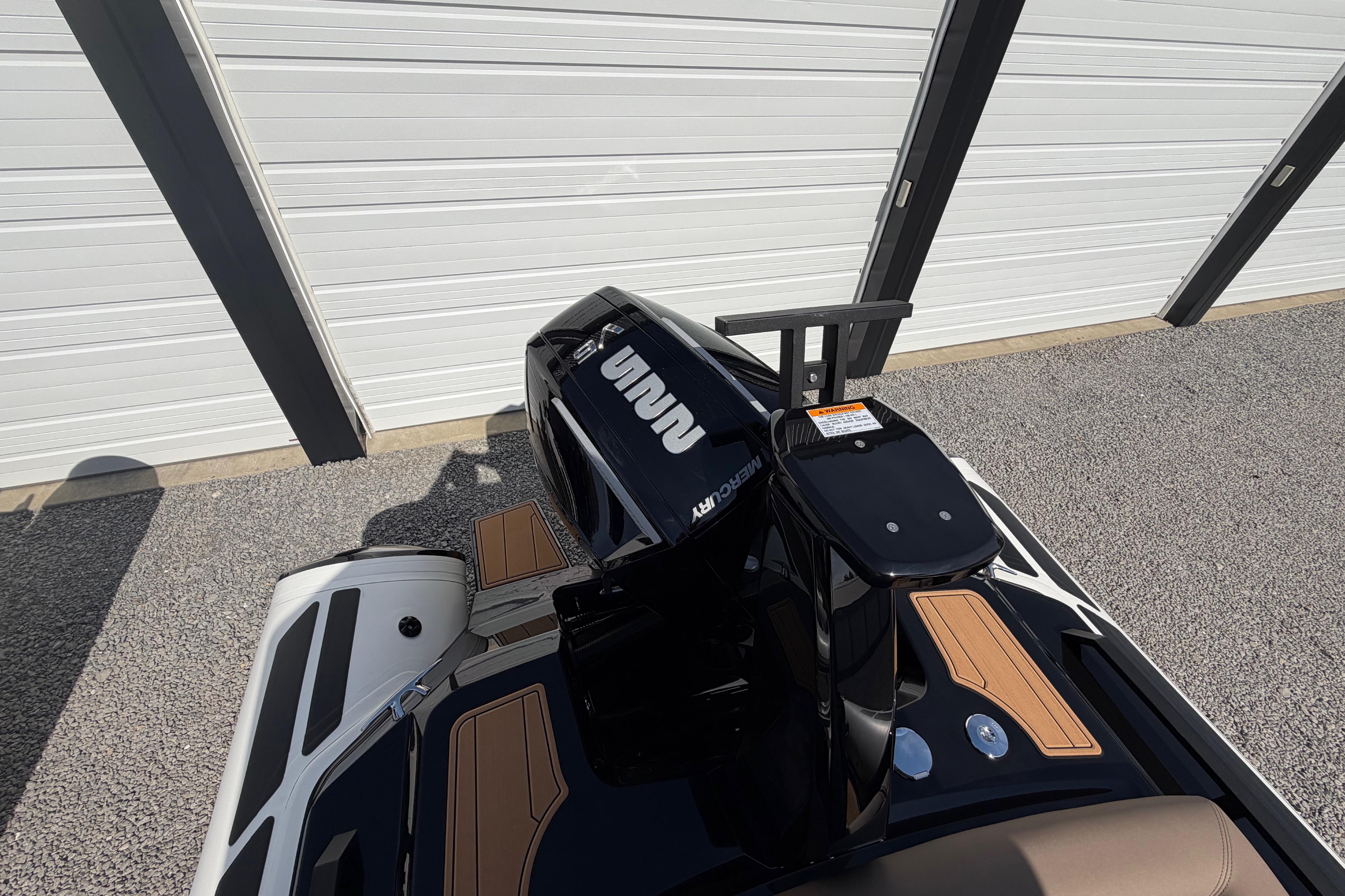 2026 Brig Eagle 6.7 boat with Mercury engine, parked near a white garage door.