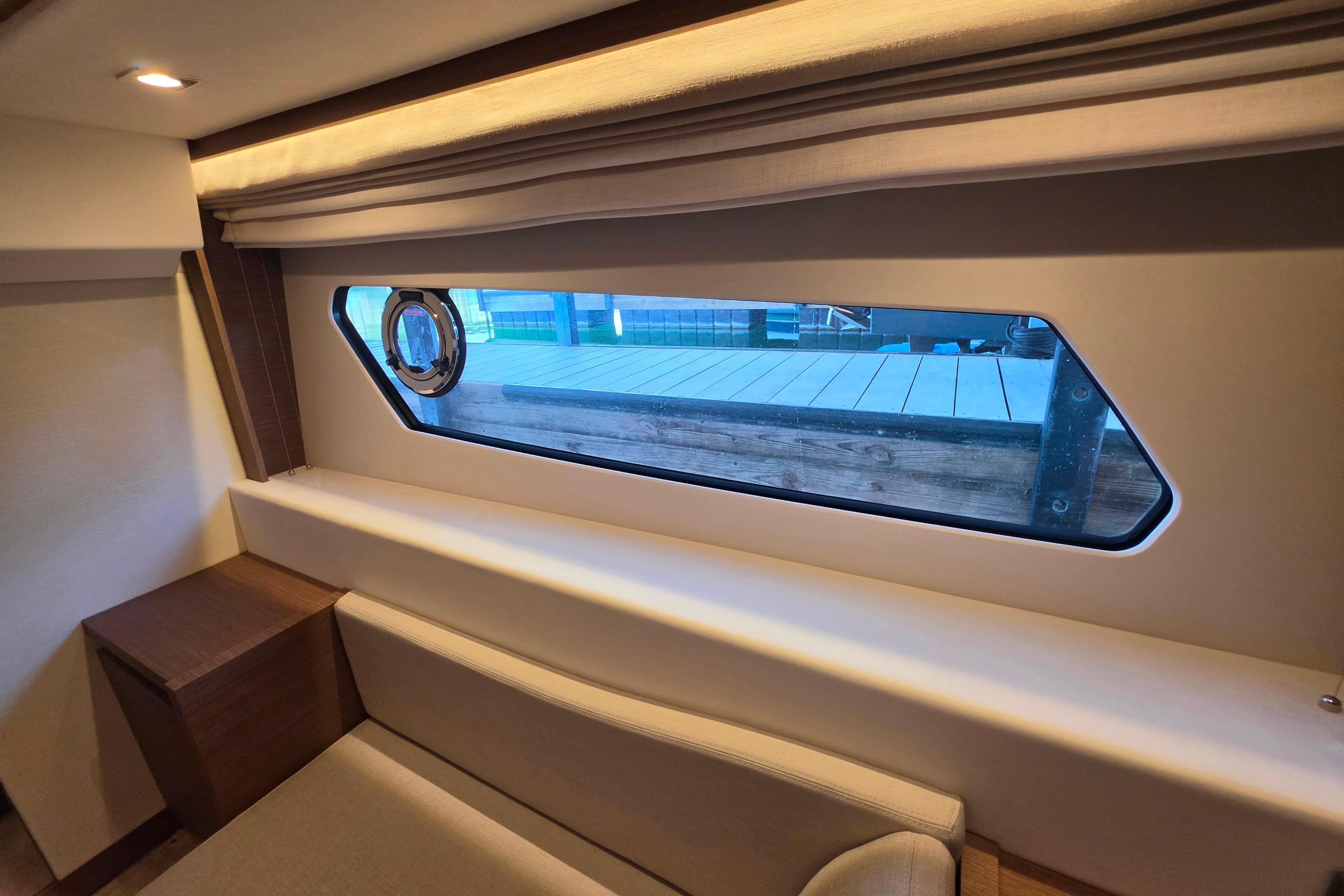 Interior view of 2025 Prestige 460 yacht cabin with window and seating area.
