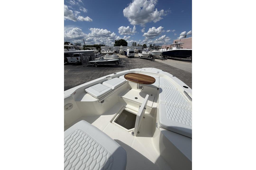 2026 Pathfinder 2800 Hybrid boat interior with cushioned seating and wooden table under a cloudy sky.