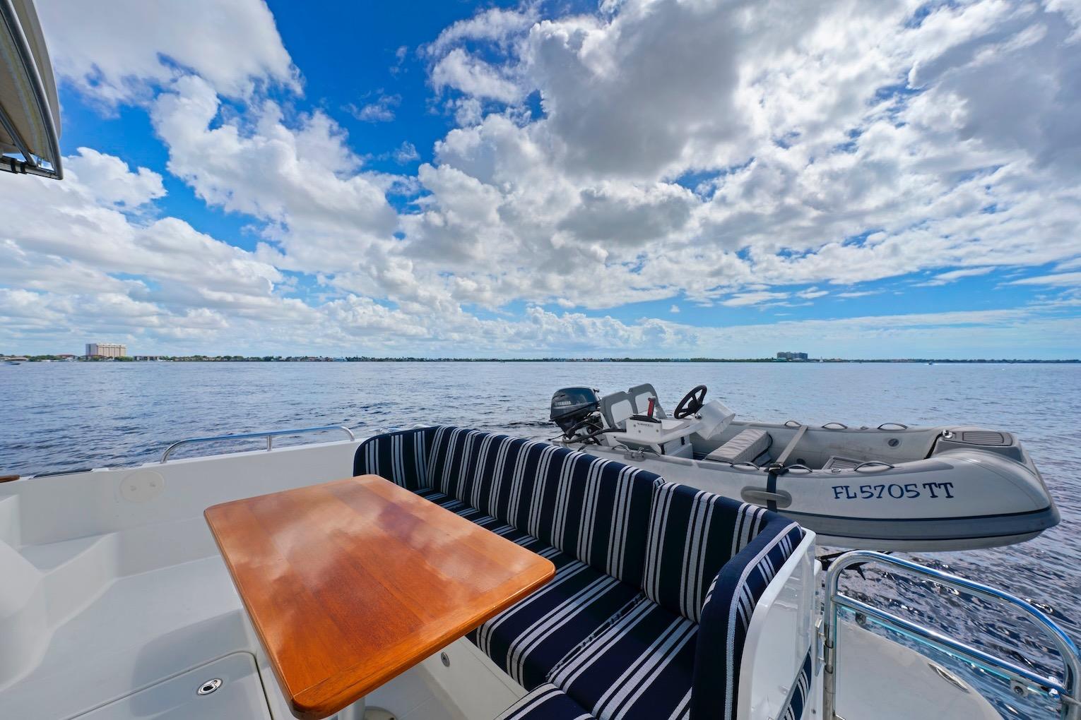 2019 Sabre 45 Salon Express yacht with striped seating, wooden table, and scenic ocean view.