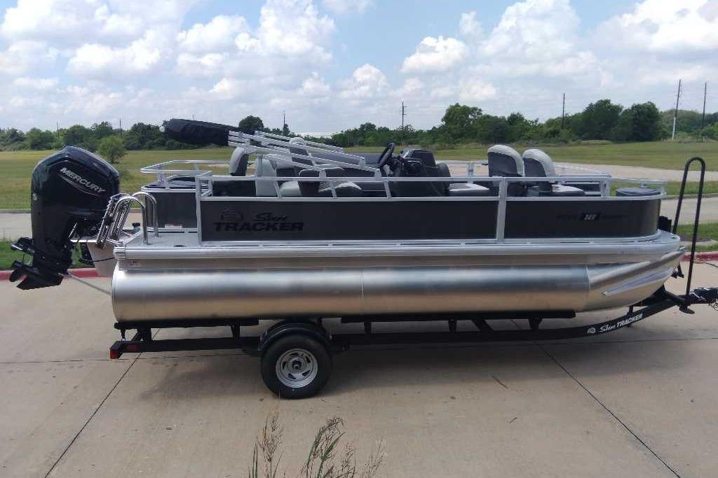 2026 Sun Tracker Bass Buggy 18 DLX pontoon boat on trailer, parked outdoors.