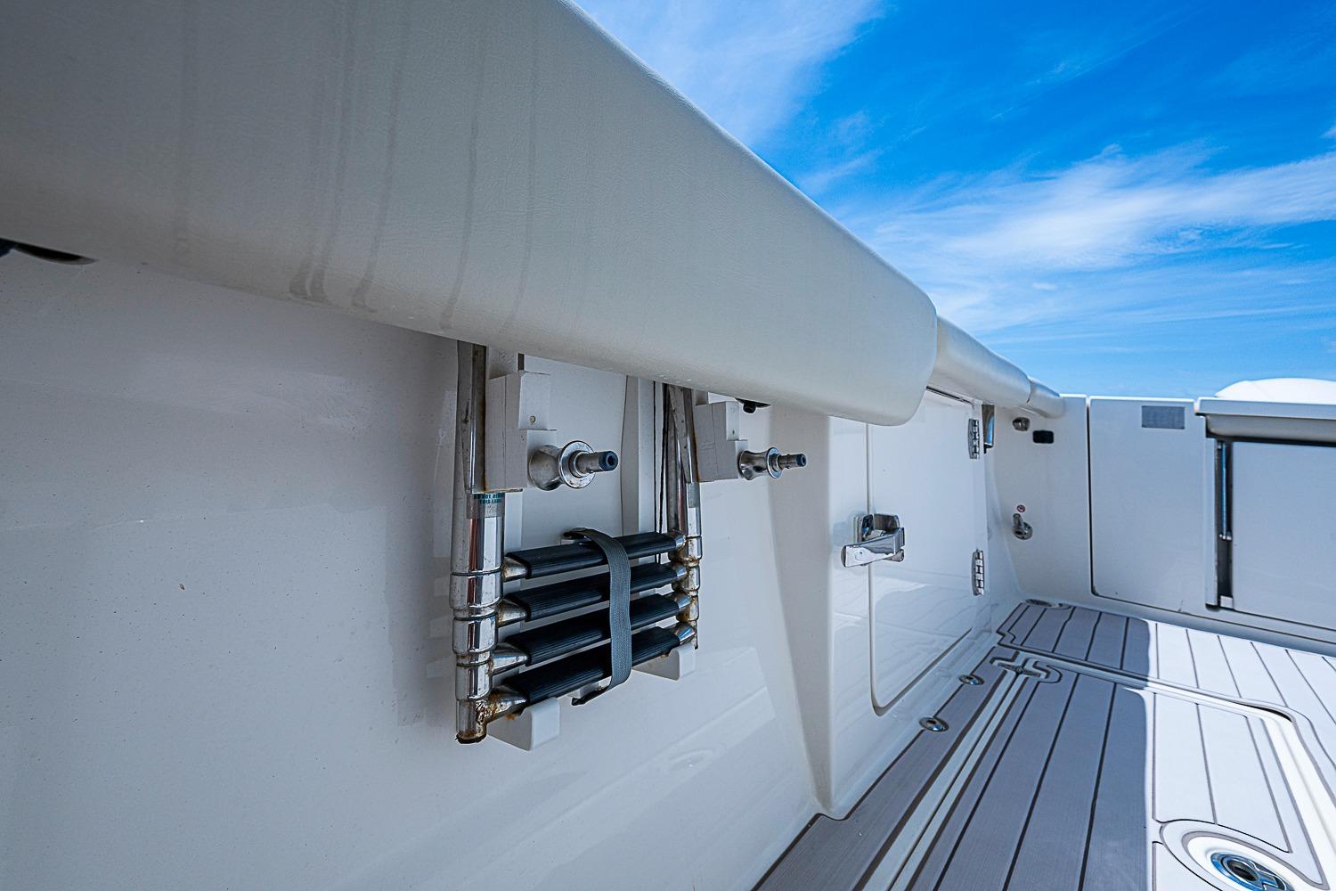 2019 Cobia 320 Center Console boat deck with storage compartments and blue sky background.