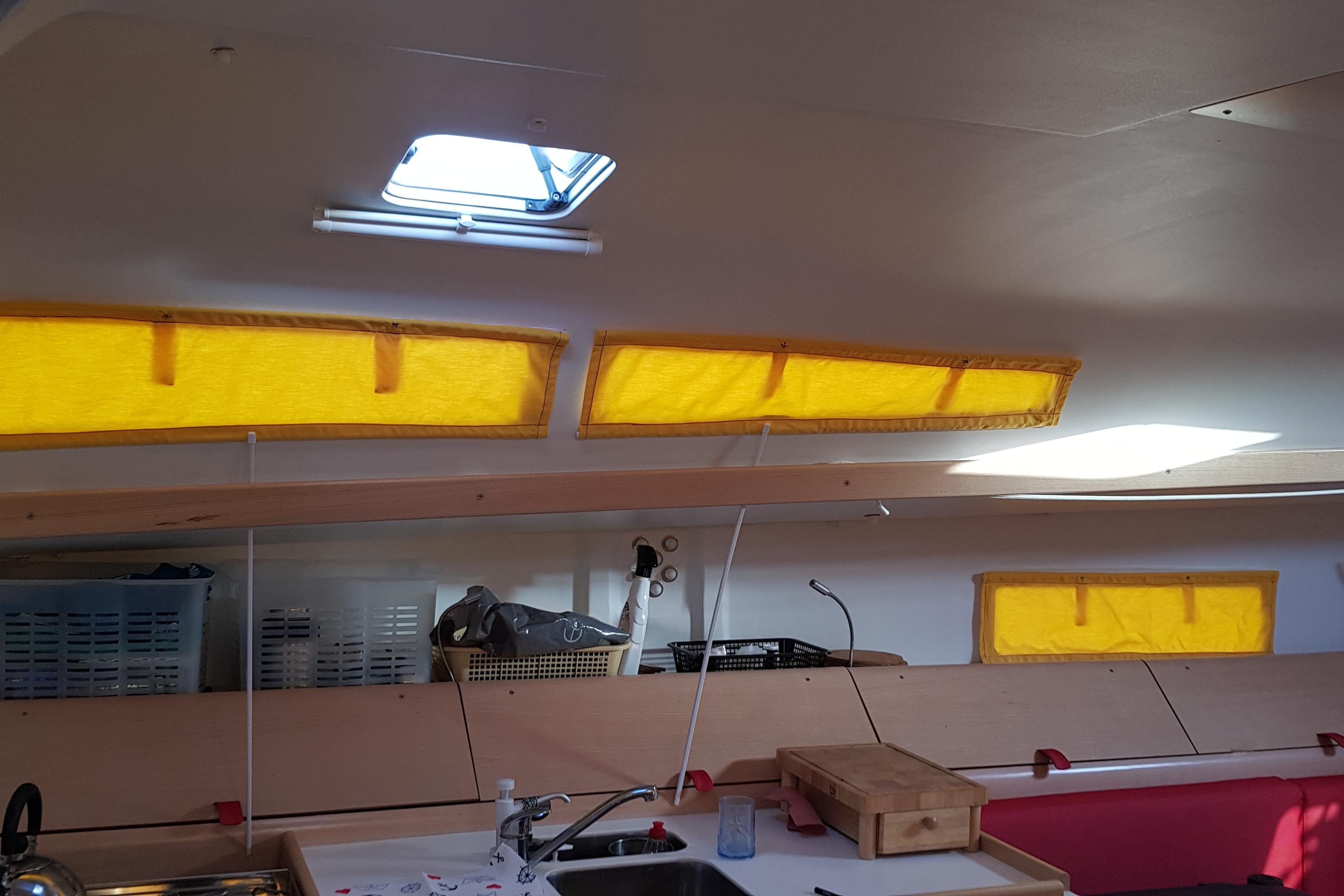 Interior of 2017 Pogo 12.50 sailboat with yellow window covers and modern kitchen area.