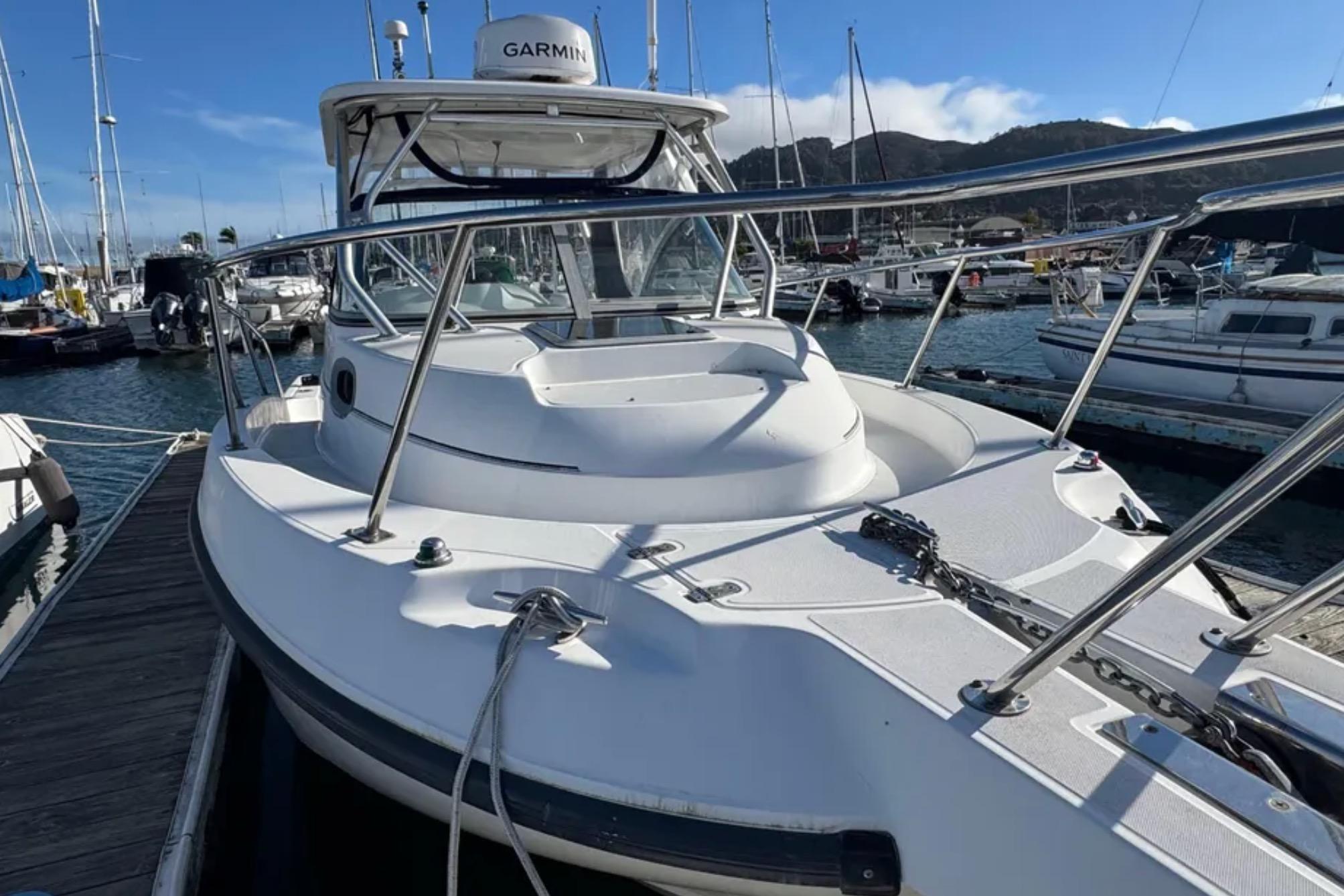 2004 Boston Whaler 255 Conquest boat docked in a marina, featuring Garmin equipment.