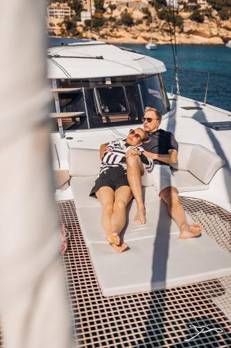 Couple relaxing on 2025 Nautitech 44 Open catamaran, enjoying sunny day at sea.