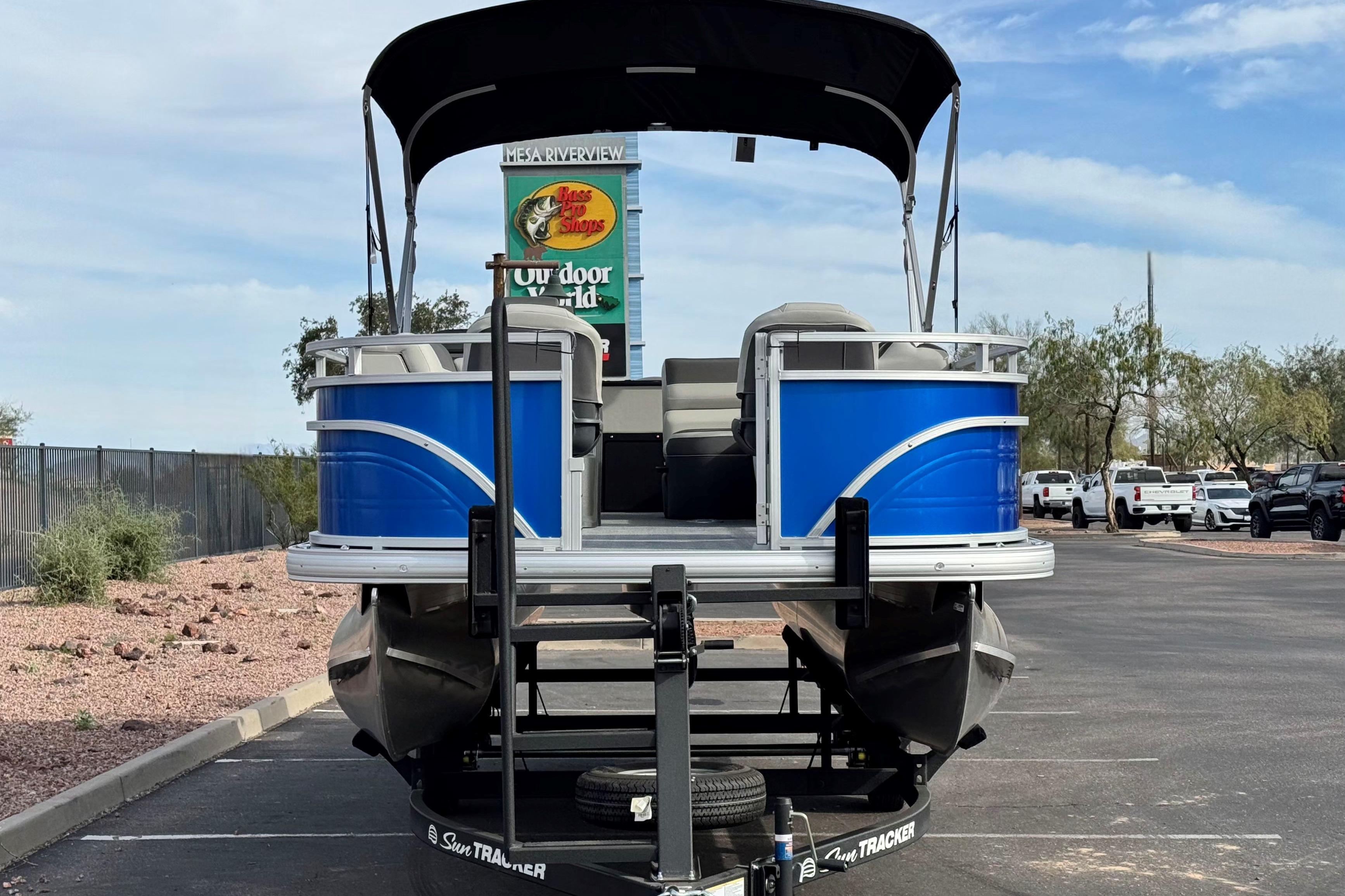 2026 Sun Tracker Fishin' Barge 20 DLX pontoon boat in parking lot, rear view.