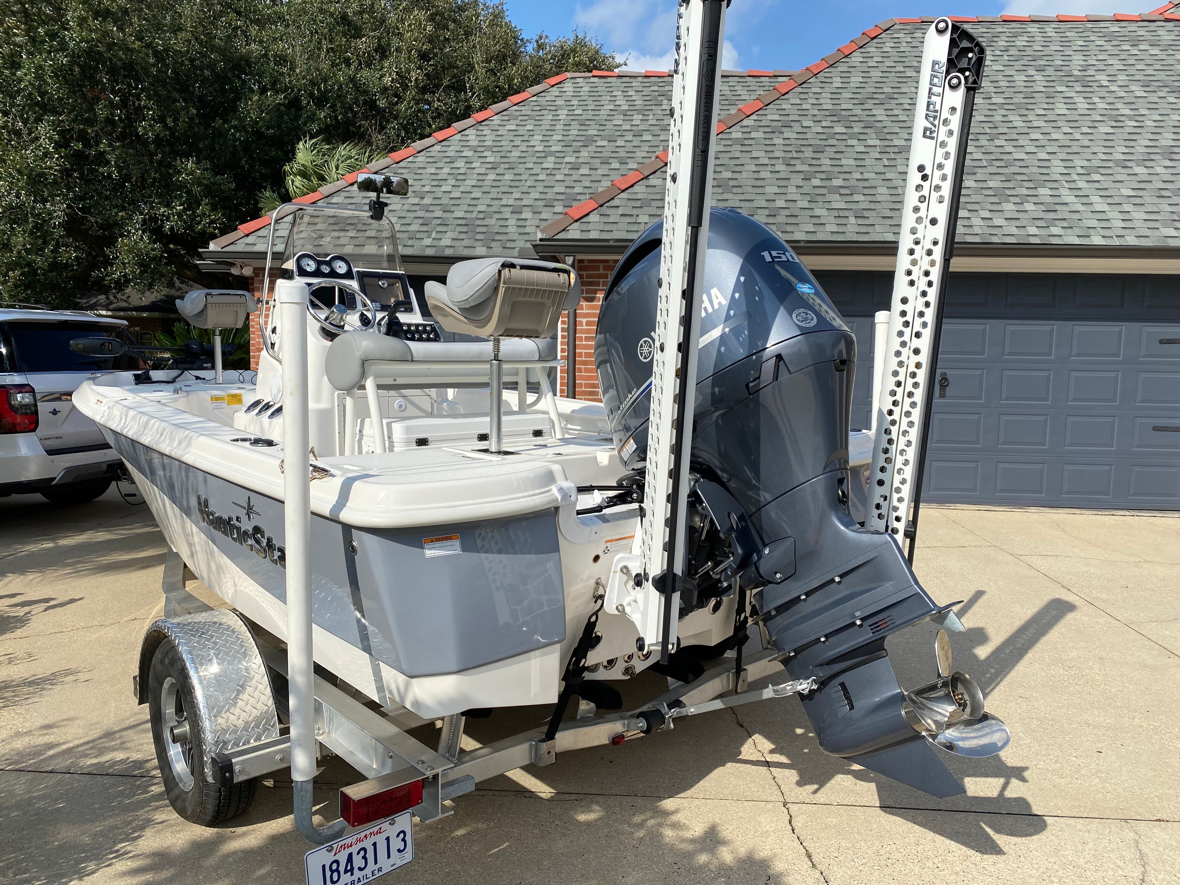 A white 2021 NauticStar 195 XTS boat on a trailer in front of a garage.