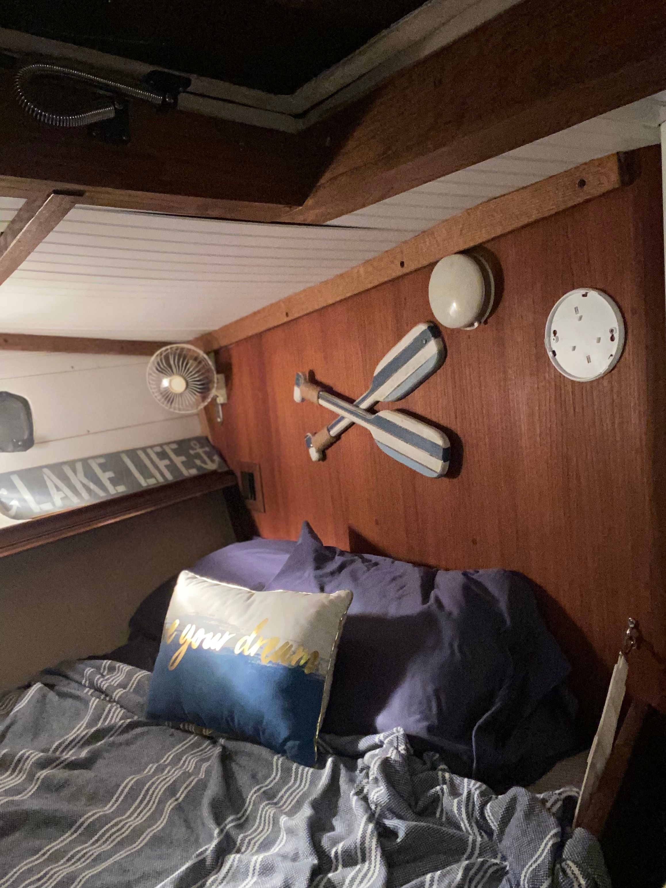 Interior of a 1983 Islander Freeport with a cozy bed and decorative paddles on the wall.