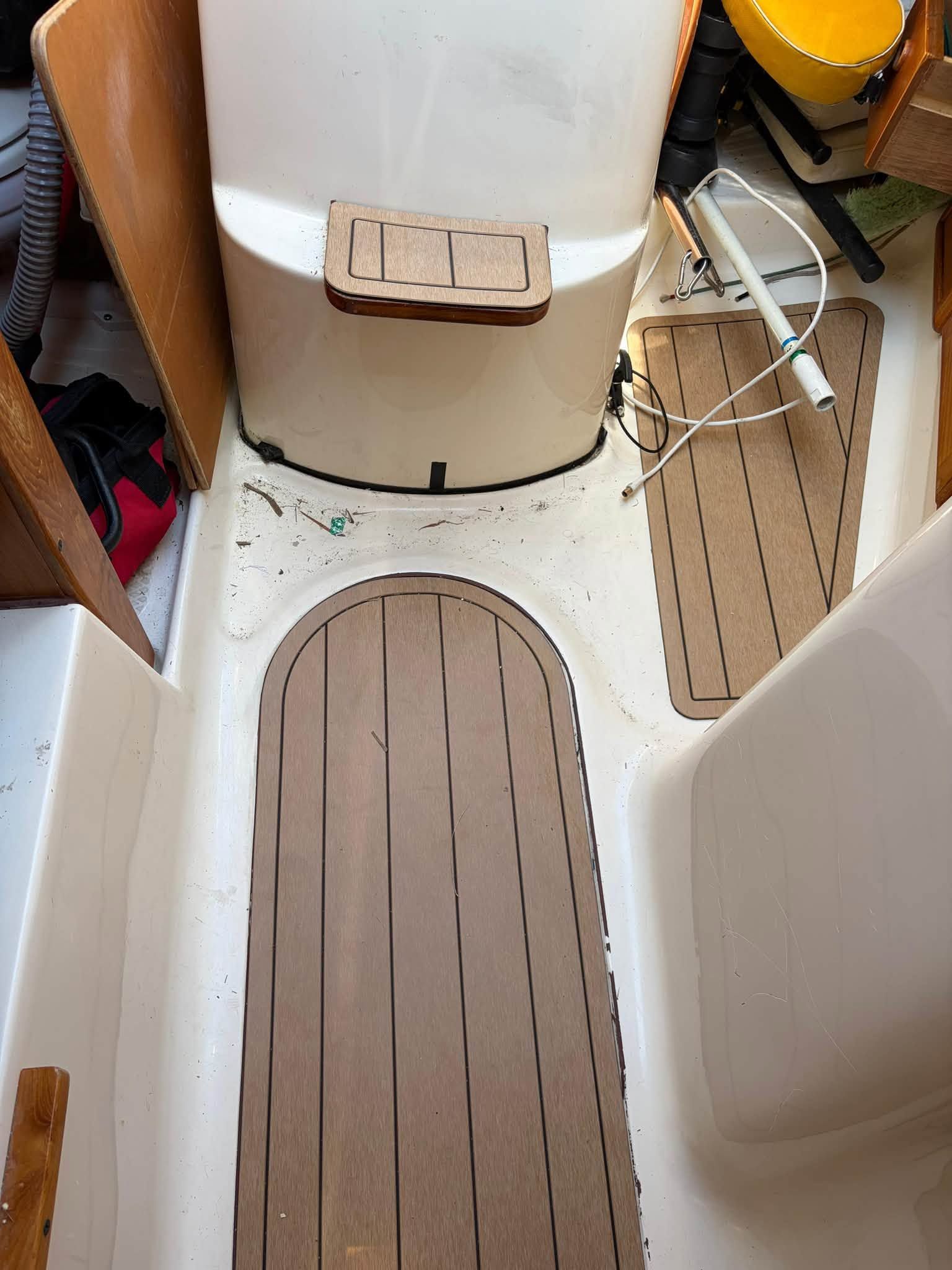 Interior of a boat with wooden flooring and a bench seat.