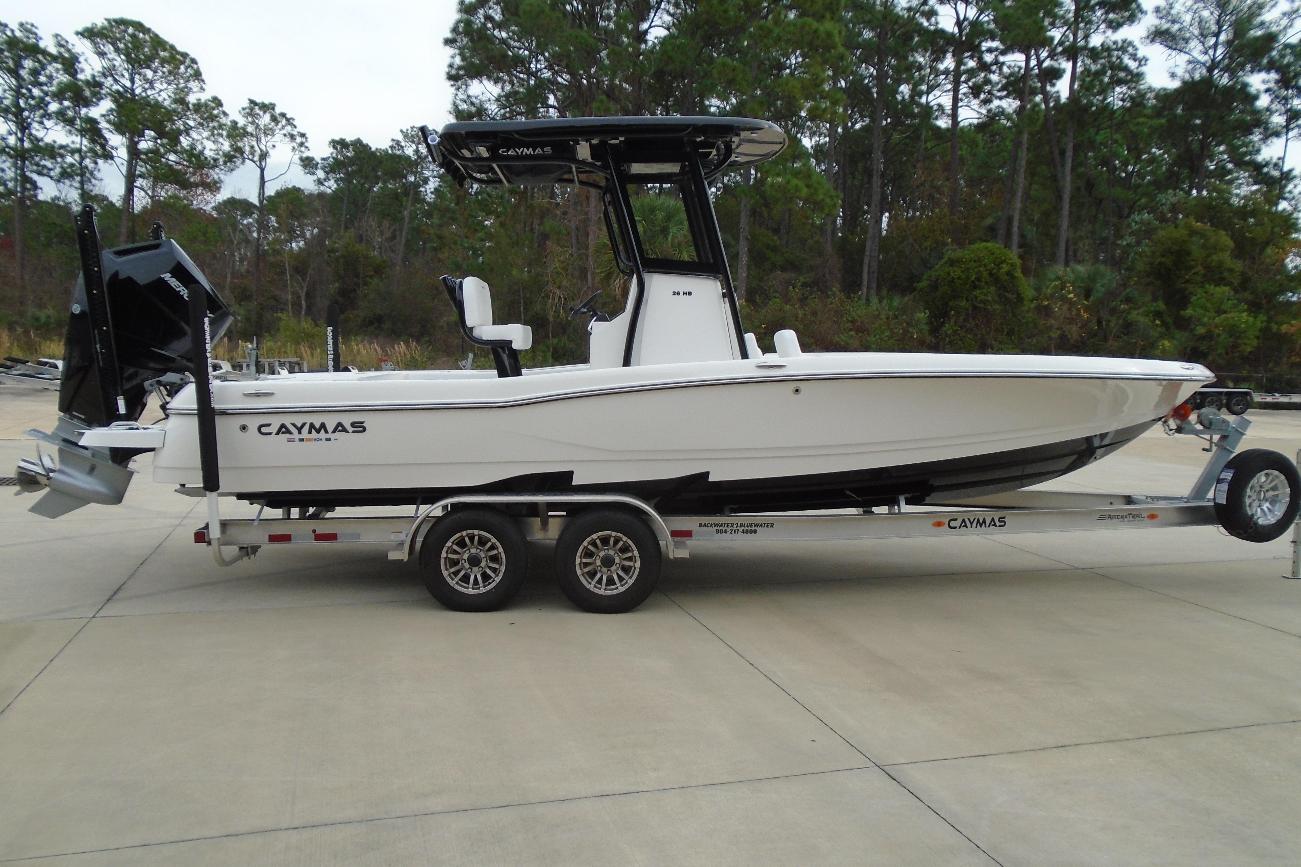 2026 Caymas 26 HB boat on trailer, parked outdoors with trees in background.