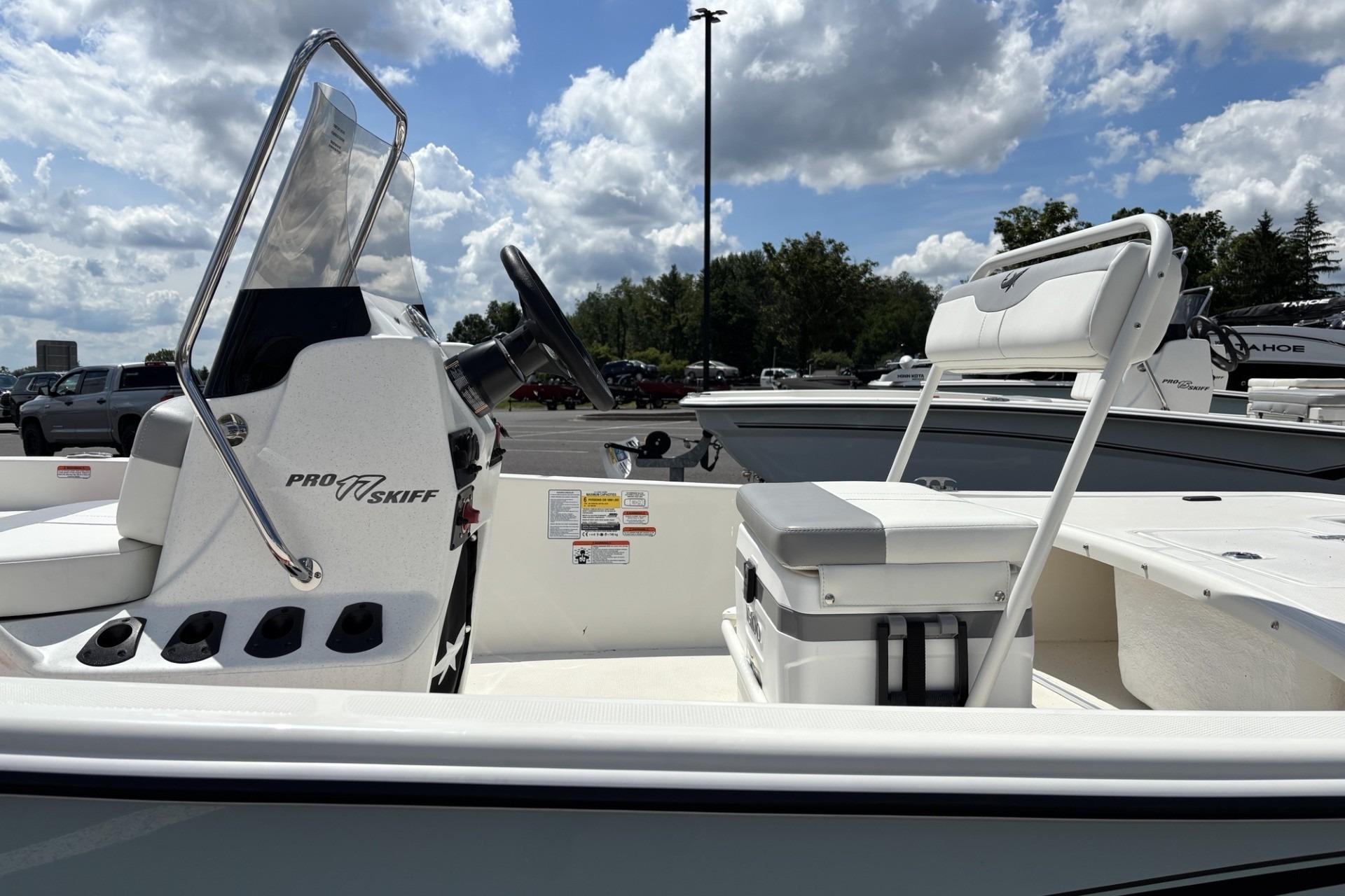 2026 Mako Pro Skiff 15 CC boat interior with steering console and seating under a cloudy sky.