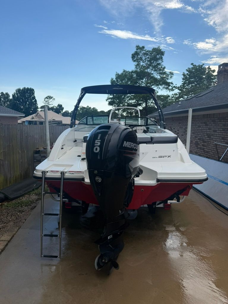A Sea Ray SPX 210 Outboard boat is on a wet driveway.