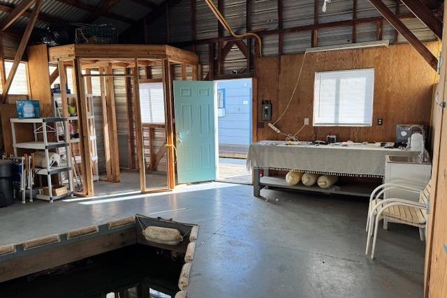 Interior of a 1960 custom boathouse with open door, dock, and storage shelves.