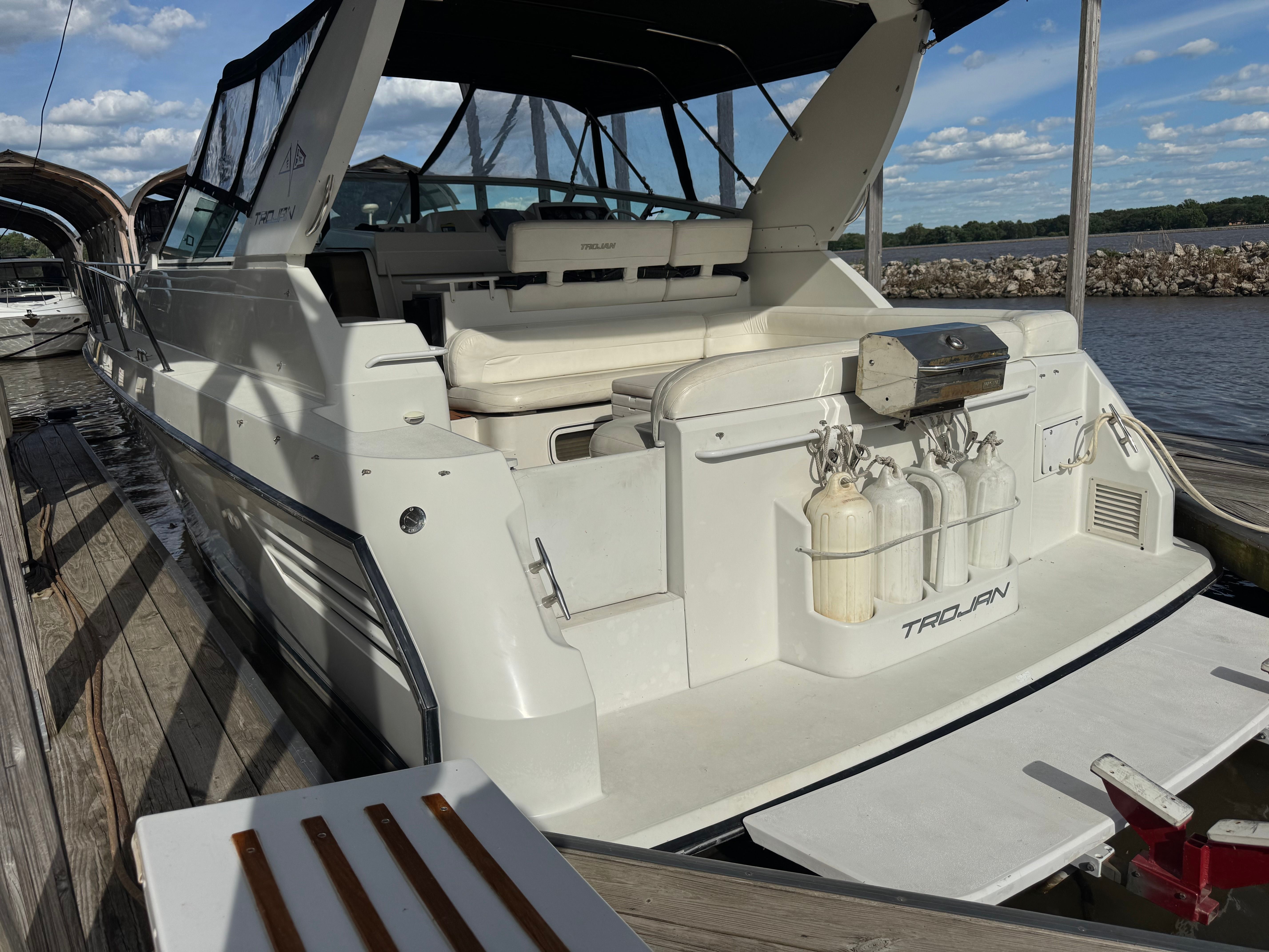 A white motor yacht docked, featuring a spacious cockpit and black canopy.