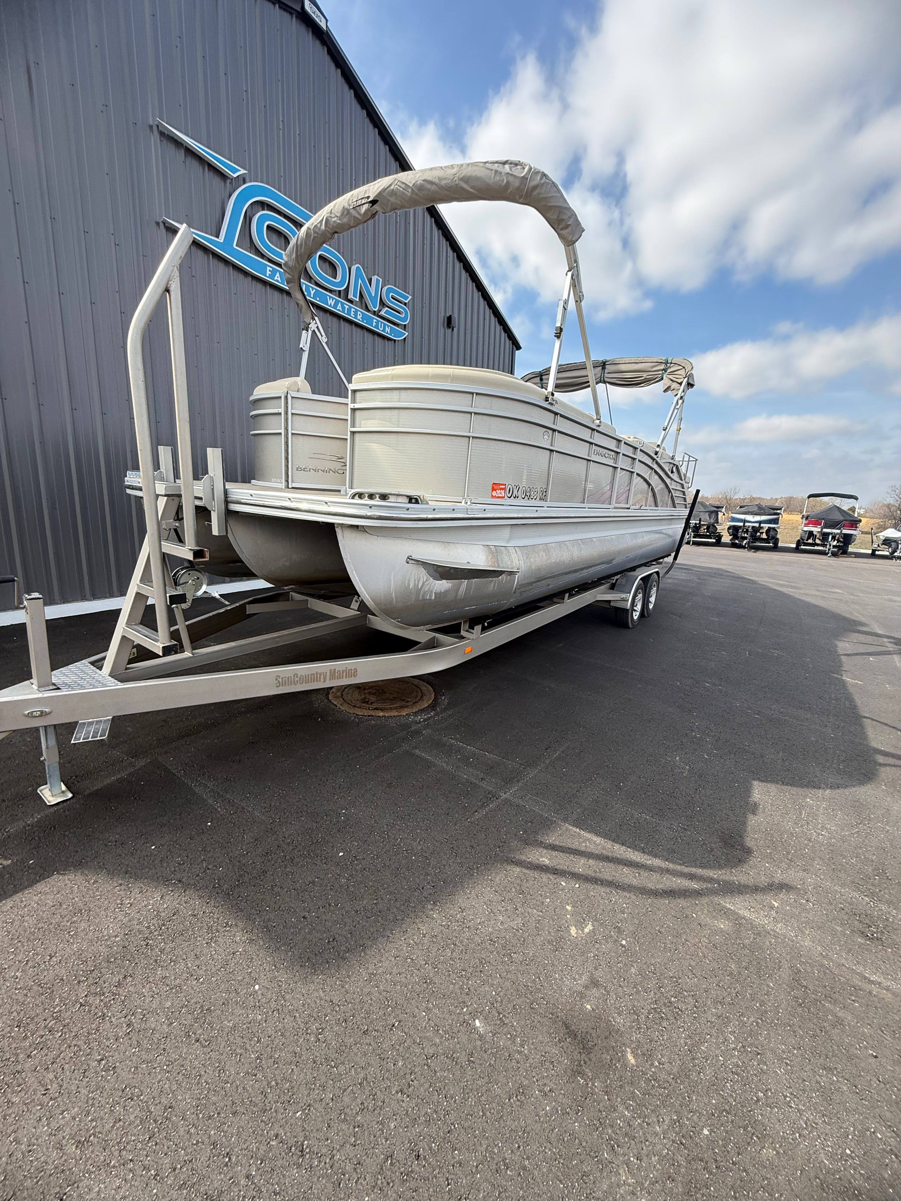 2014 Bennington 2575RCW-I/O pontoon boat on trailer outside building.