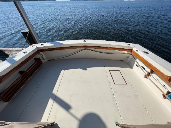 The image shows the stern of a boat with wood trim, overlooking the water.