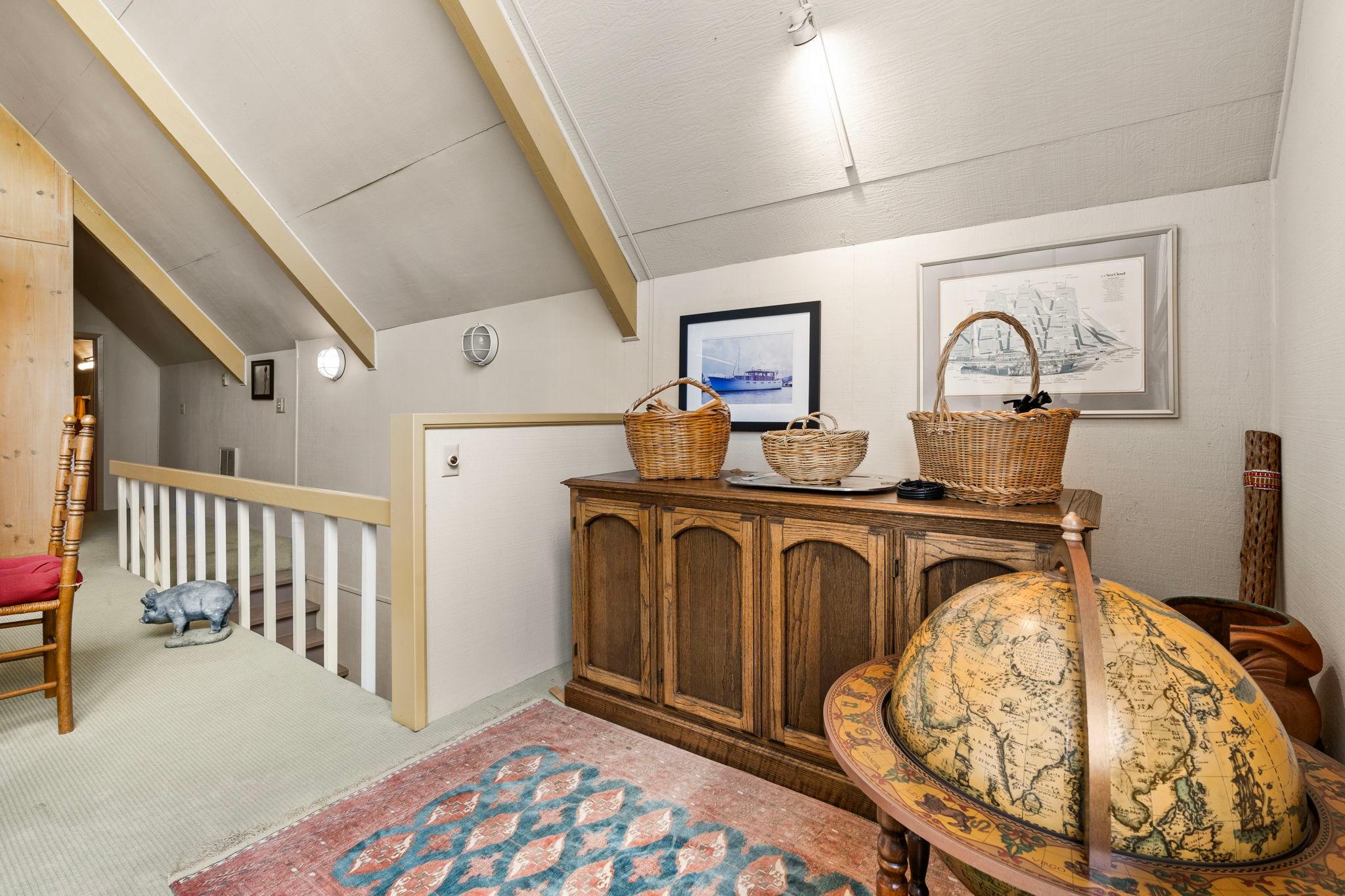 Cozy boathouse interior with vintage decor, globe, wicker baskets, and nautical artwork, built in 1976.