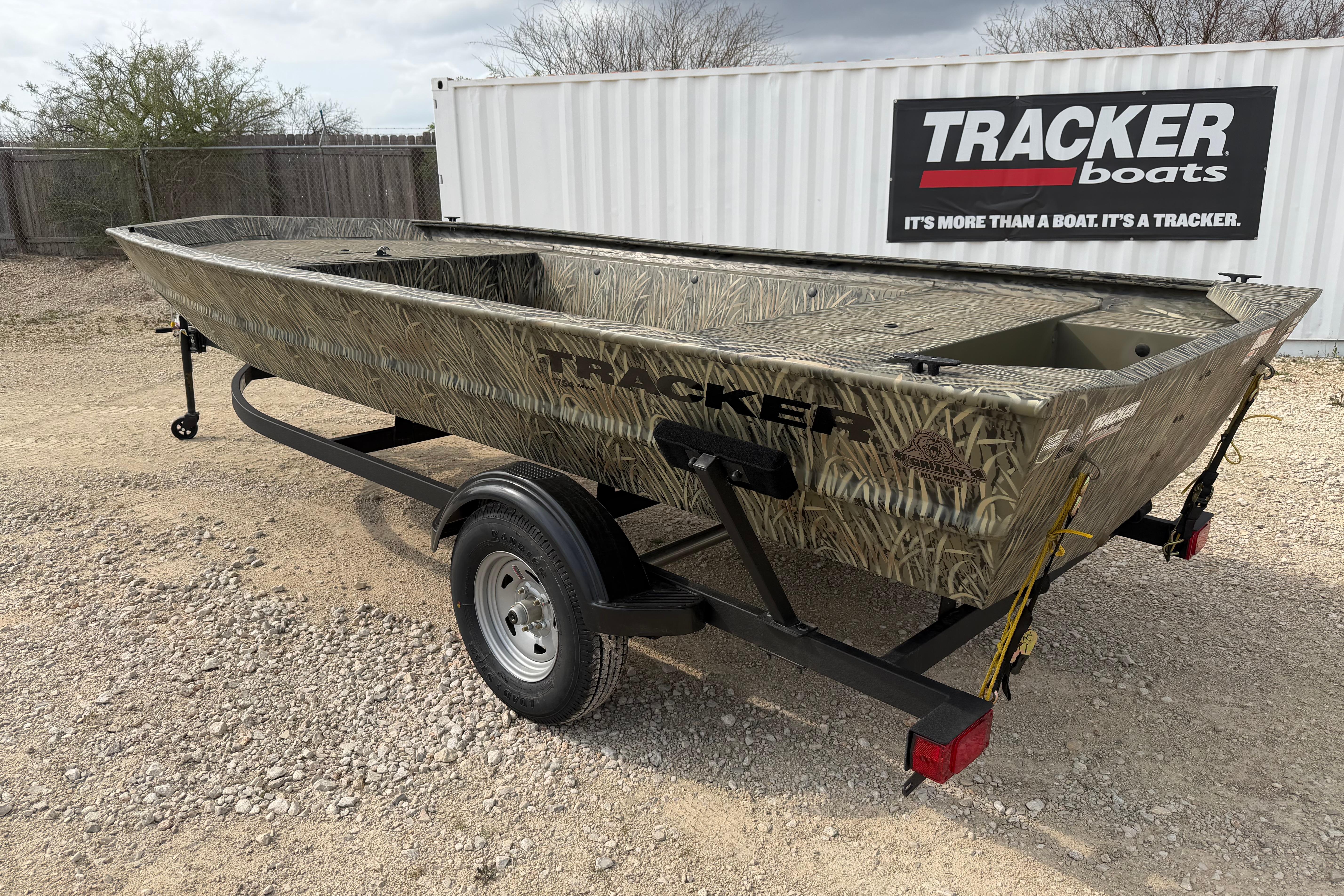 2026 Tracker Grizzly 1754 Utility boat on trailer, camo design, parked outdoors.