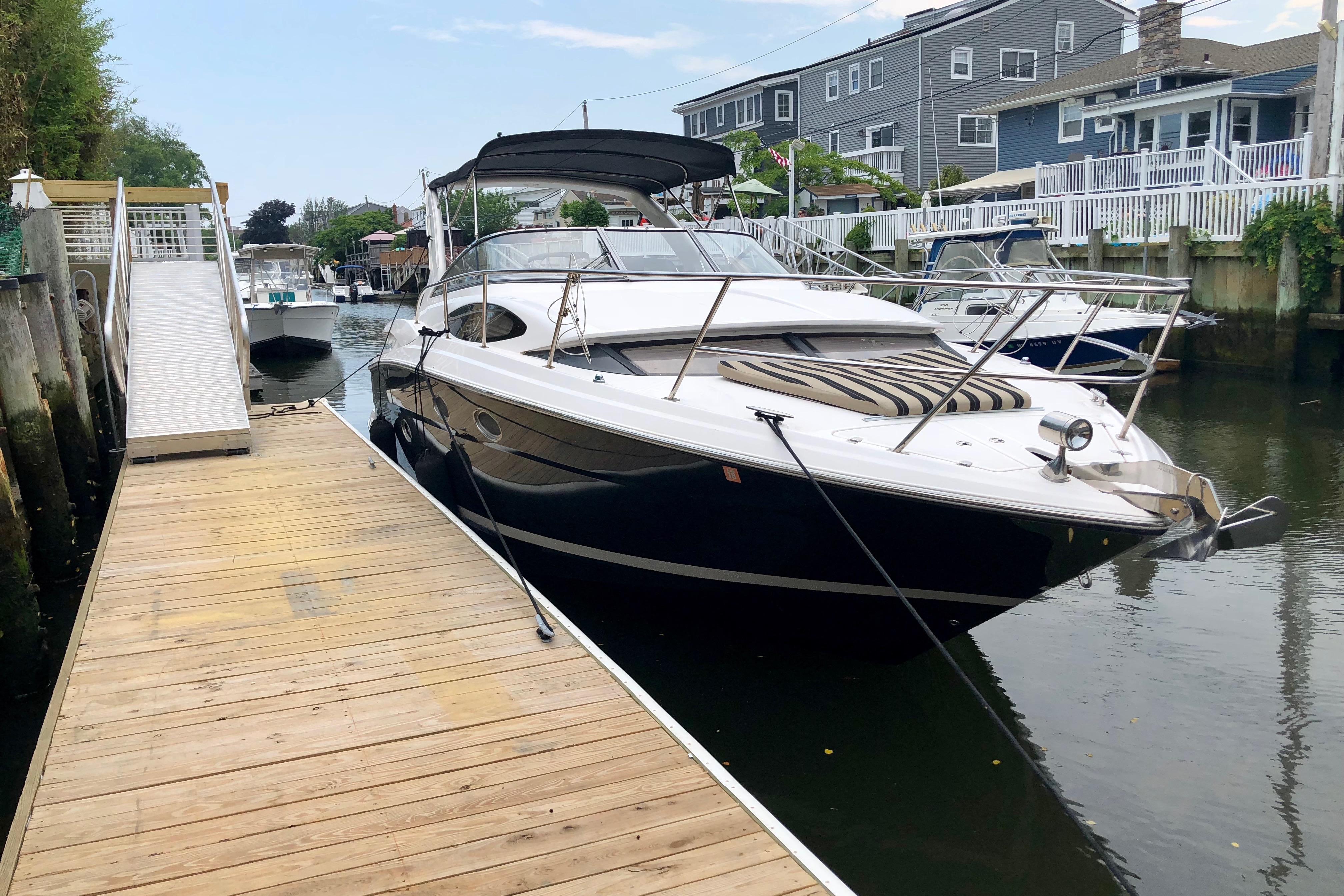 2012 Regal 35 Express Cruiser docked beside a wooden pier in a residential canal.