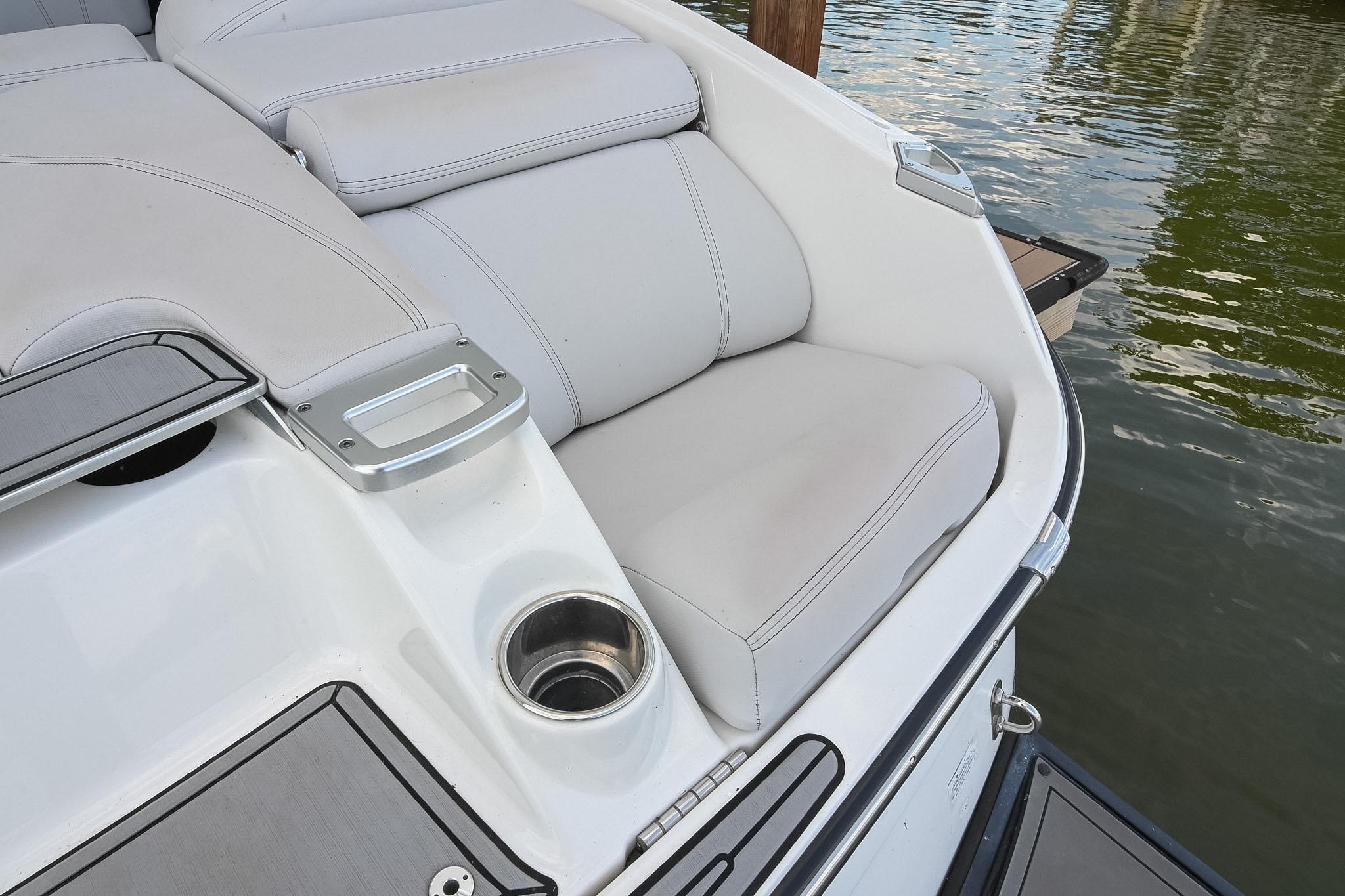 2018 MasterCraft X23 boat with white cushioned seating and cup holder by the water.