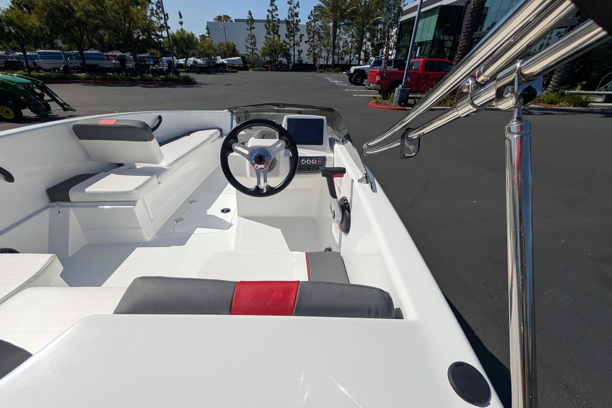 2026 Tahoe T16 boat interior with steering wheel, seating, and control panel in a parking lot.
