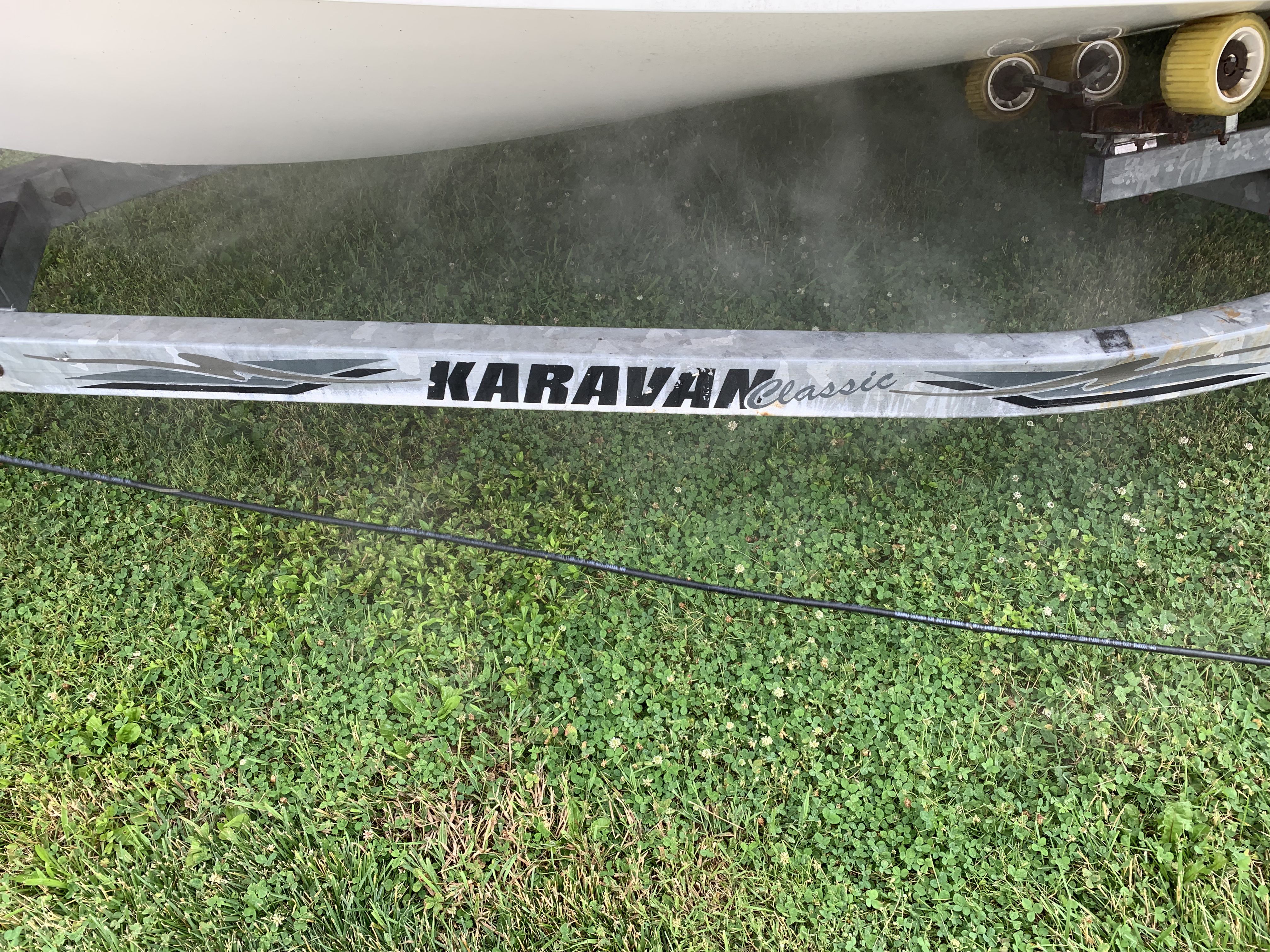 A boat on a Karavan Classic trailer on grass.