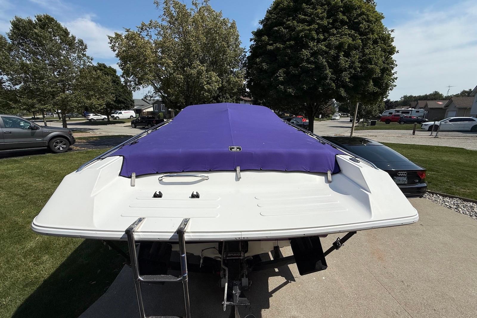 1995 Checkmate Persuader 261 boat with purple cover, parked outdoors.