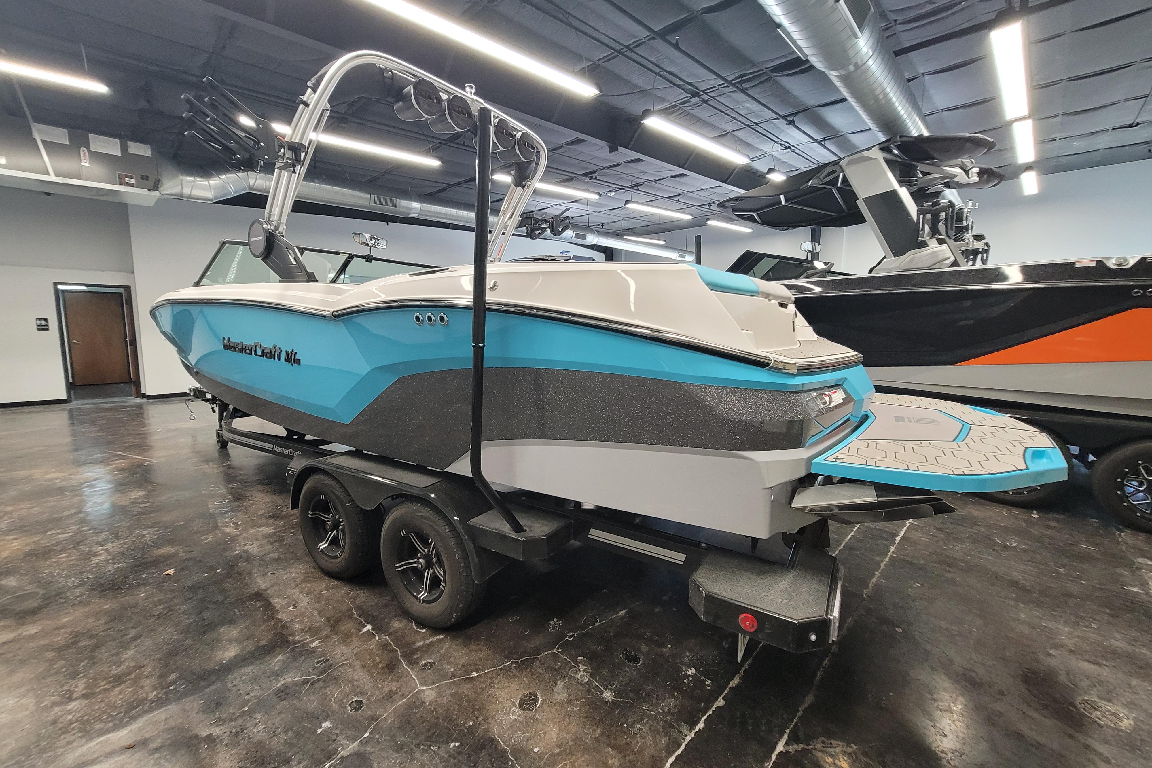 2024 MasterCraft NXT24 boat in showroom, featuring sleek design and vibrant blue accents.