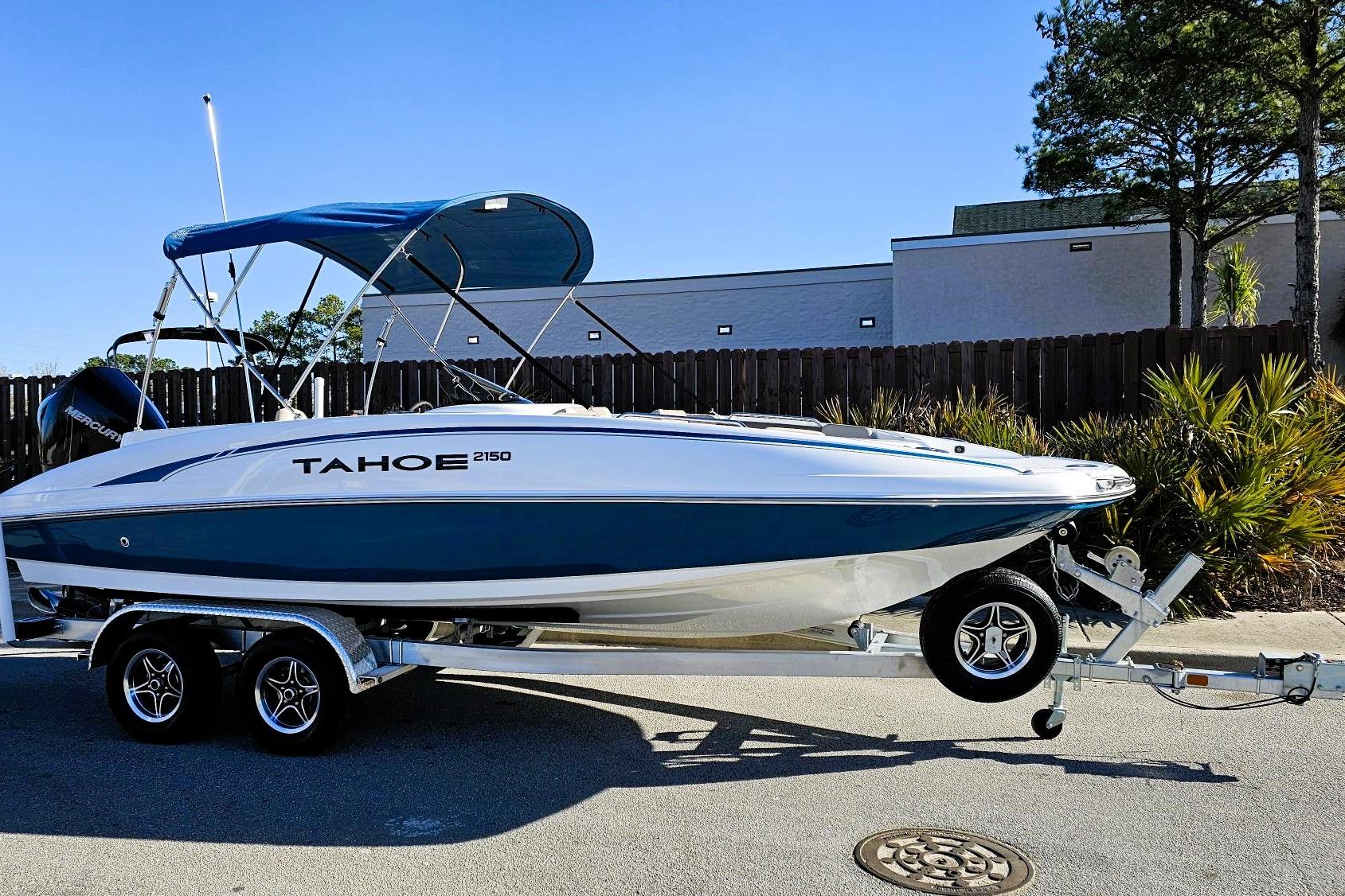 2026 Tahoe 2150 boat on trailer with blue canopy, parked outdoors.