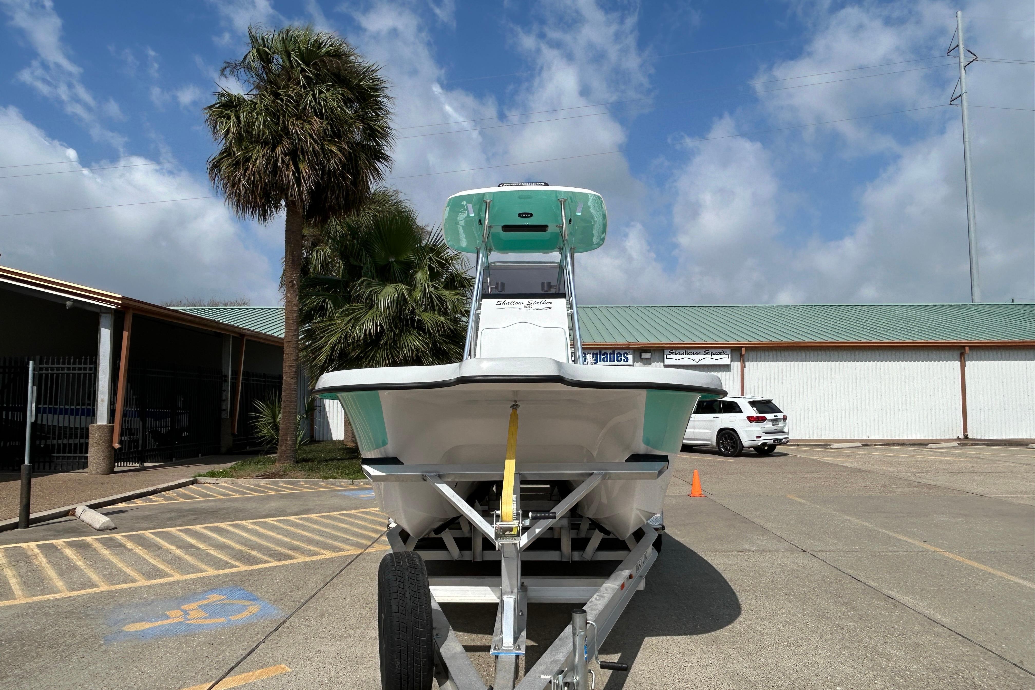 2026 Shallow Stalker "The Boss" boat on trailer, parked under blue sky.