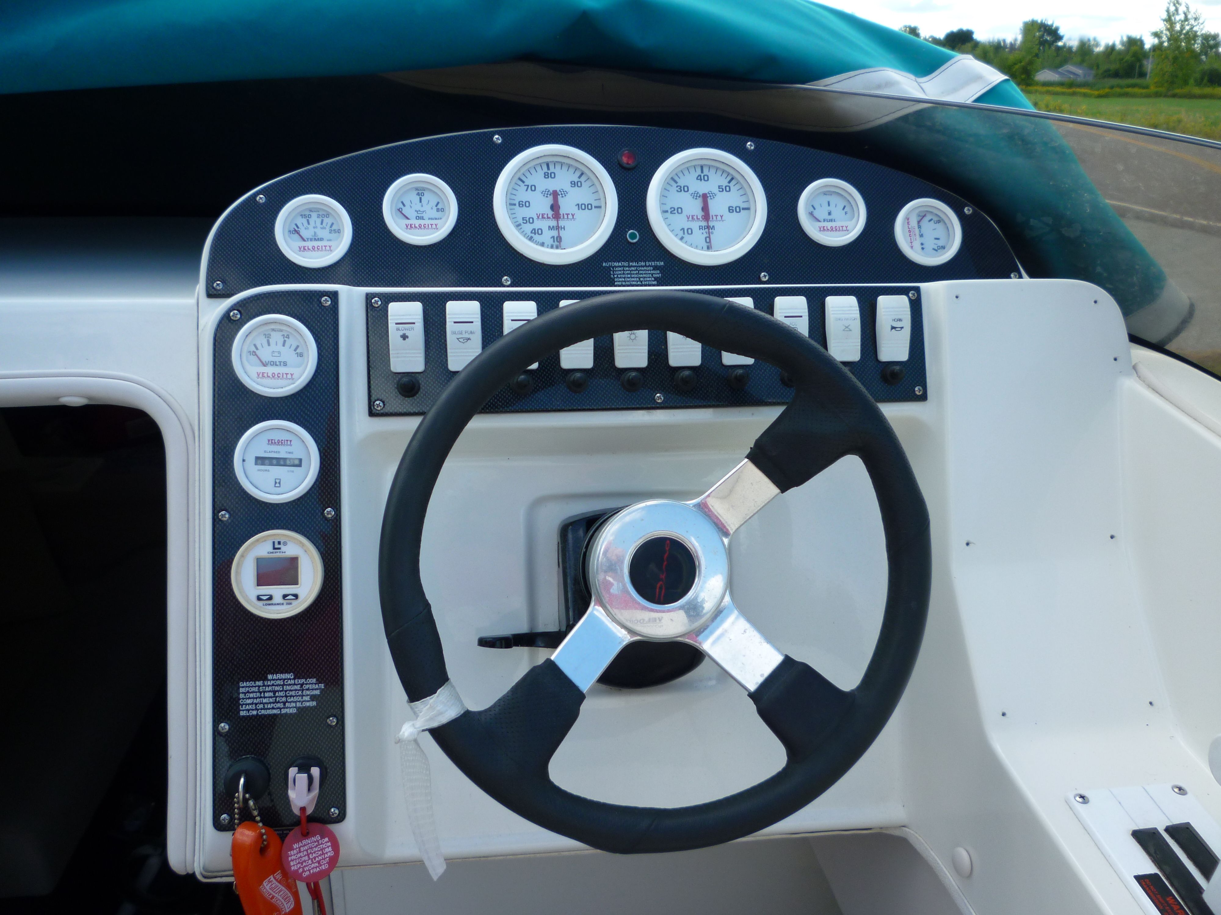Steering wheel and dashboard of a 2000 Velocity 280 boat with gauges and controls.