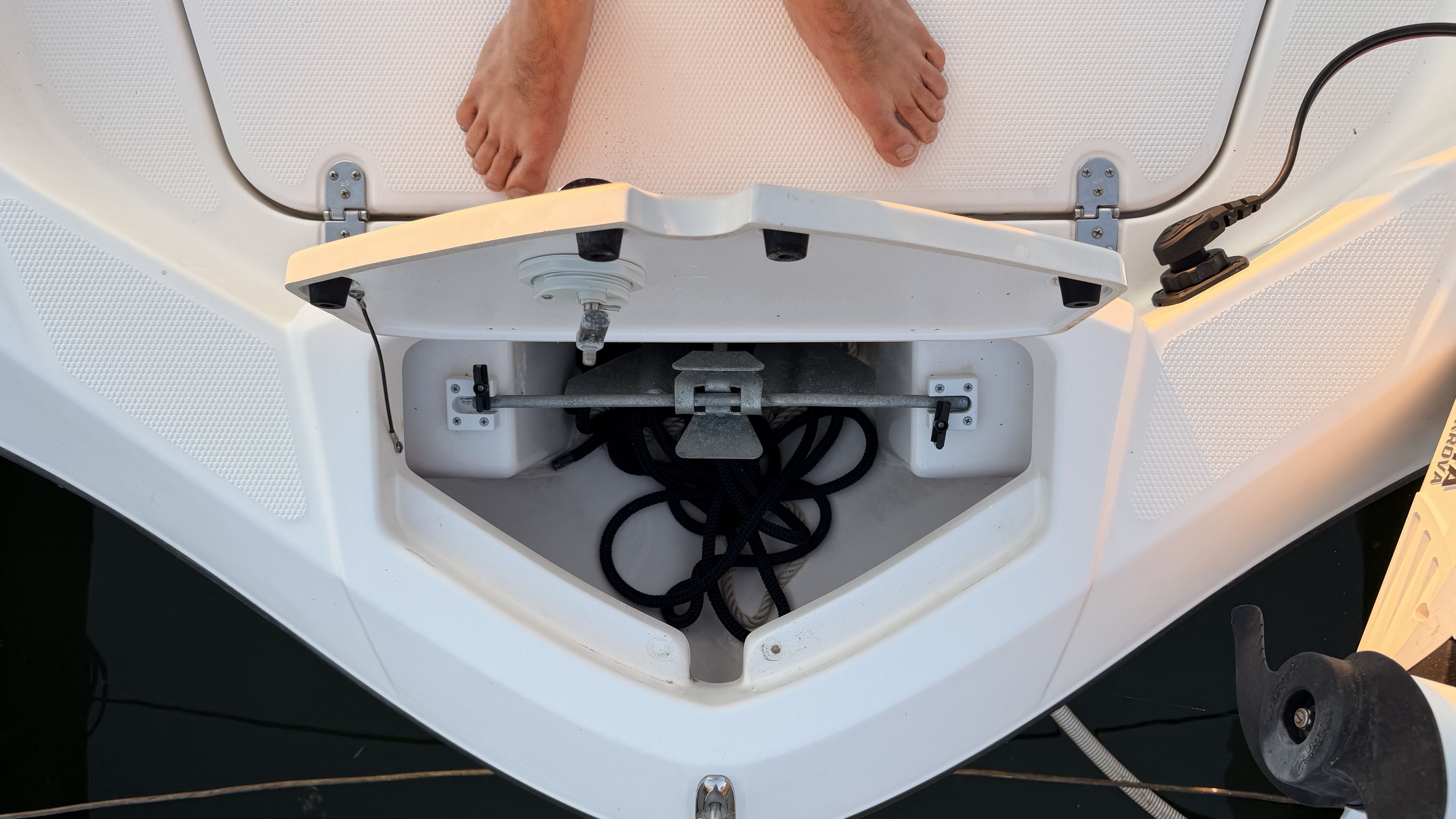 An open storage compartment on a boat with ropes and an anchor.