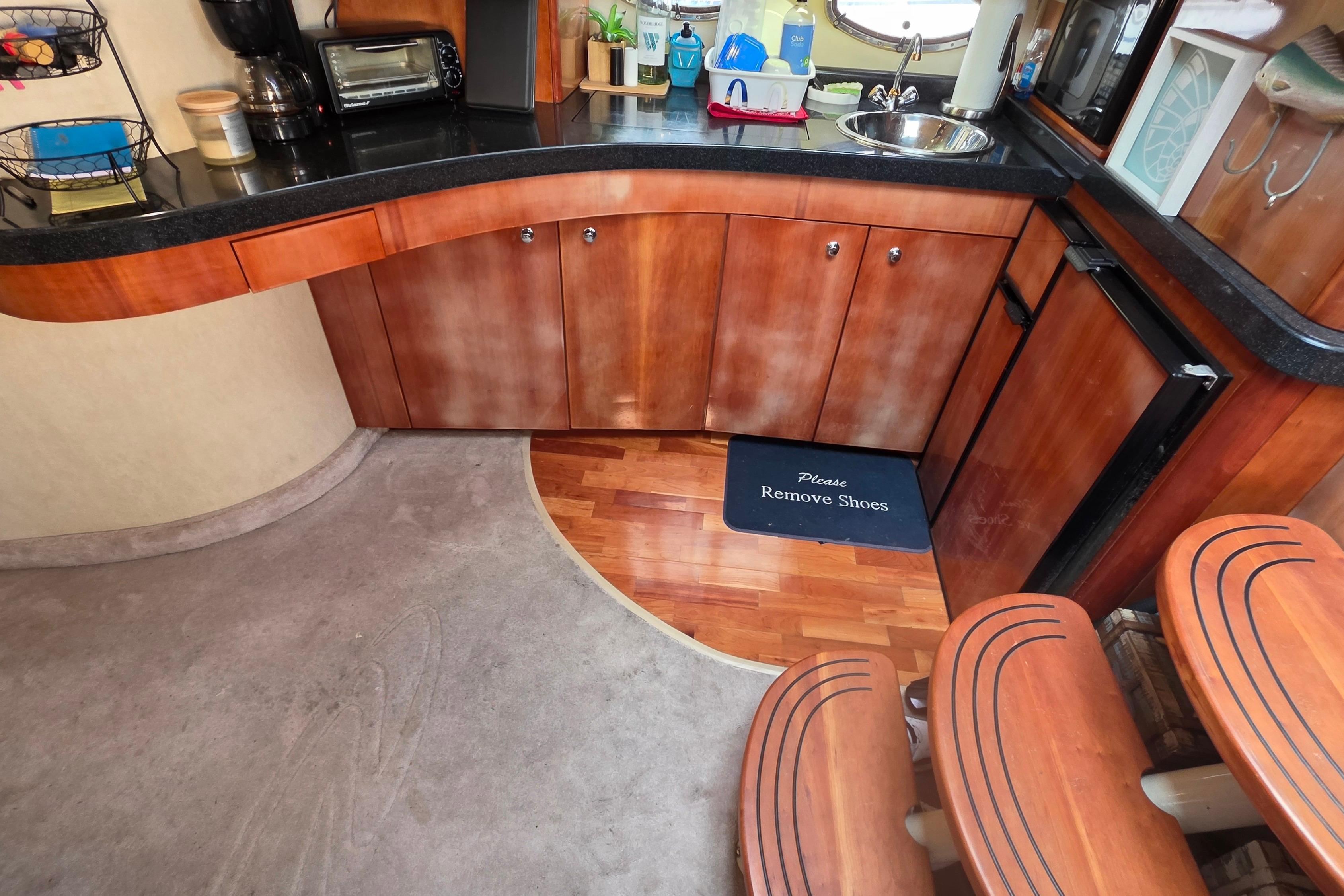 Interior of 2002 Regal Commodore 4260 yacht with kitchenette and "Please Remove Shoes" mat.
