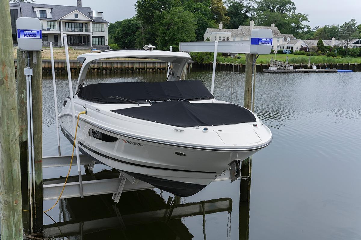 2018 Sea Ray SLX 350 boat docked on a lift by waterfront homes.