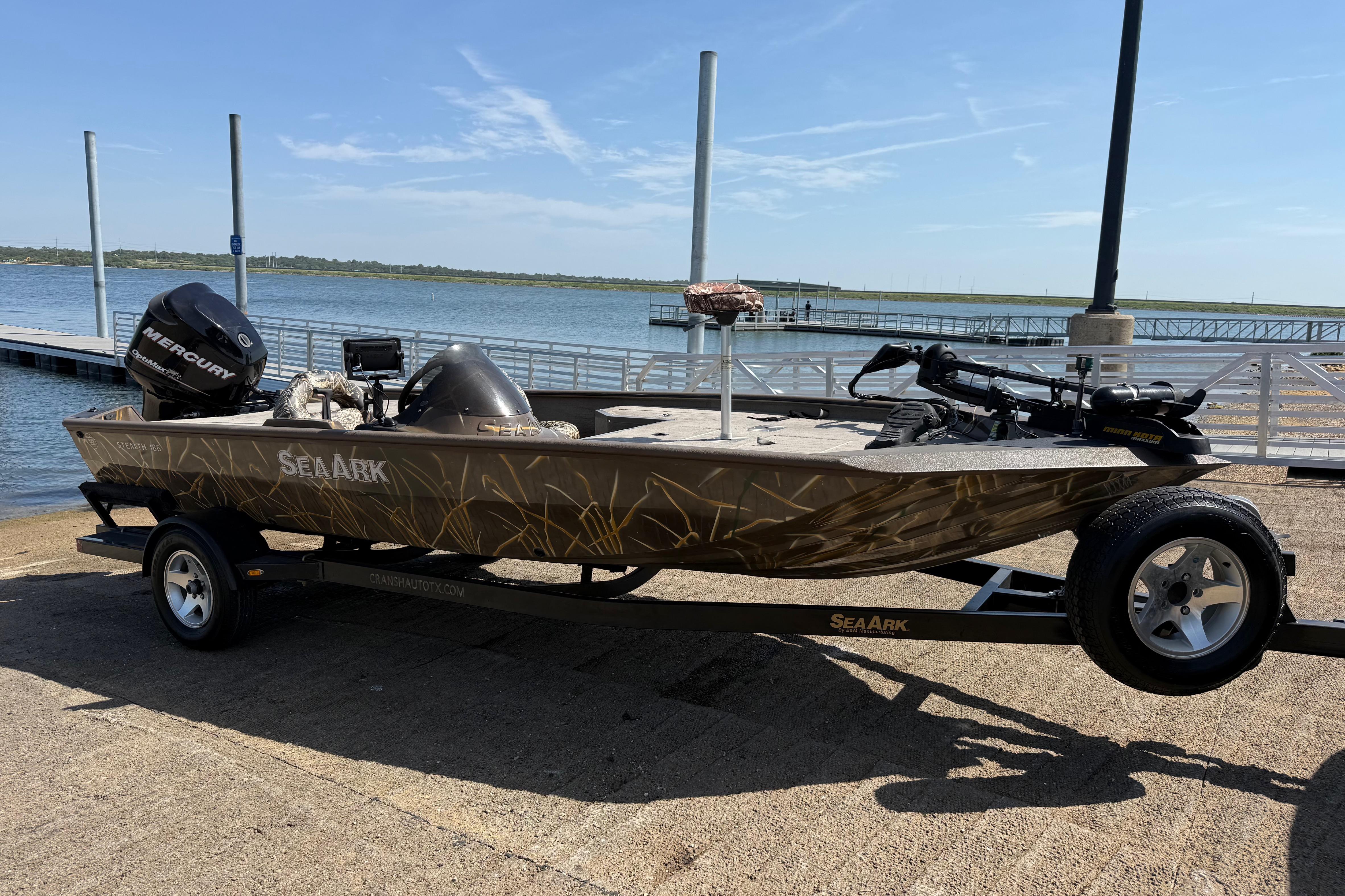 2010 SeaArk Stealth 190 boat on trailer by the waterfront, featuring a Mercury outboard motor.