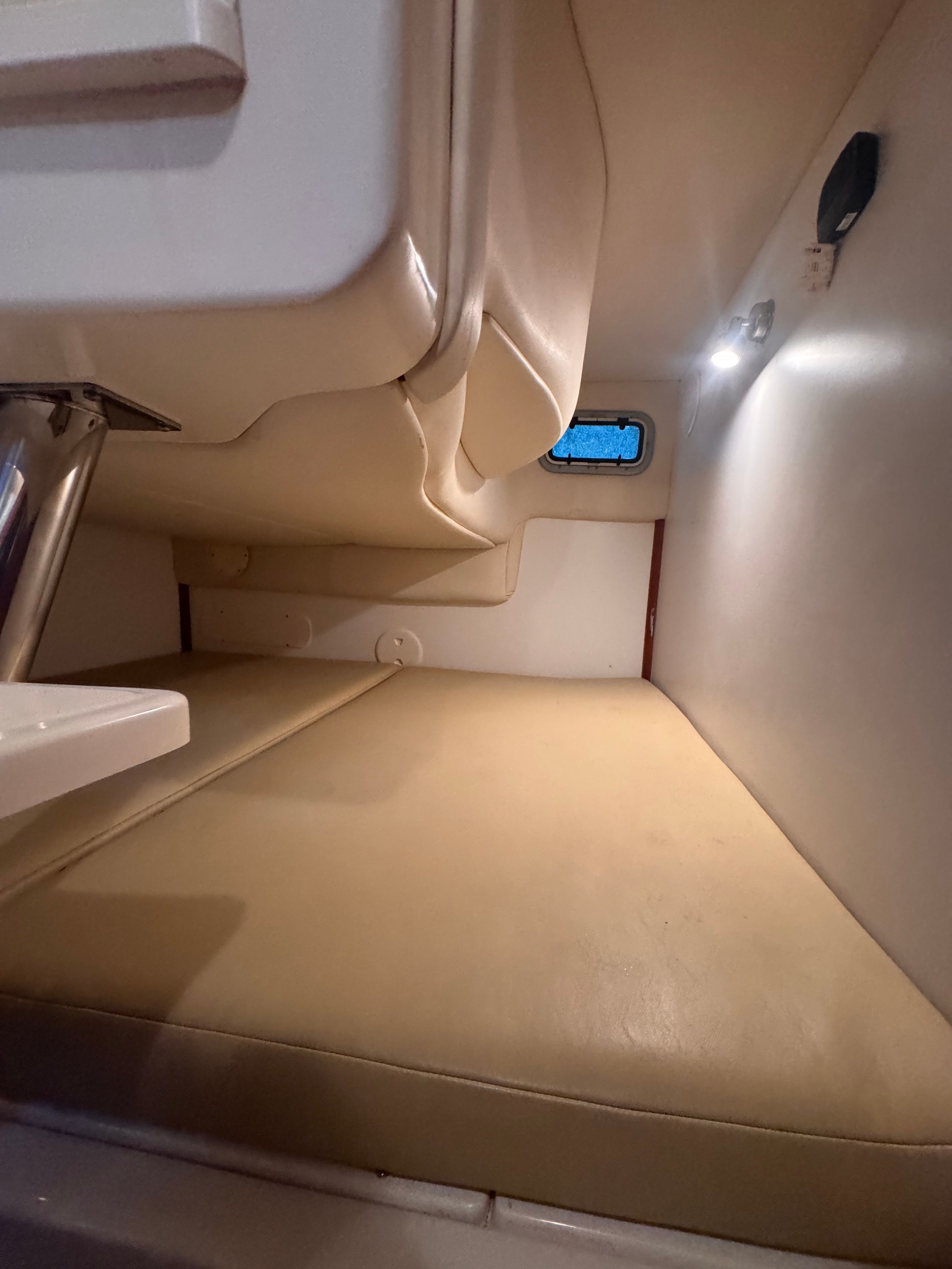 Interior of the 2006 Boston Whaler 305 Conquest with cushioned seating area and small window.