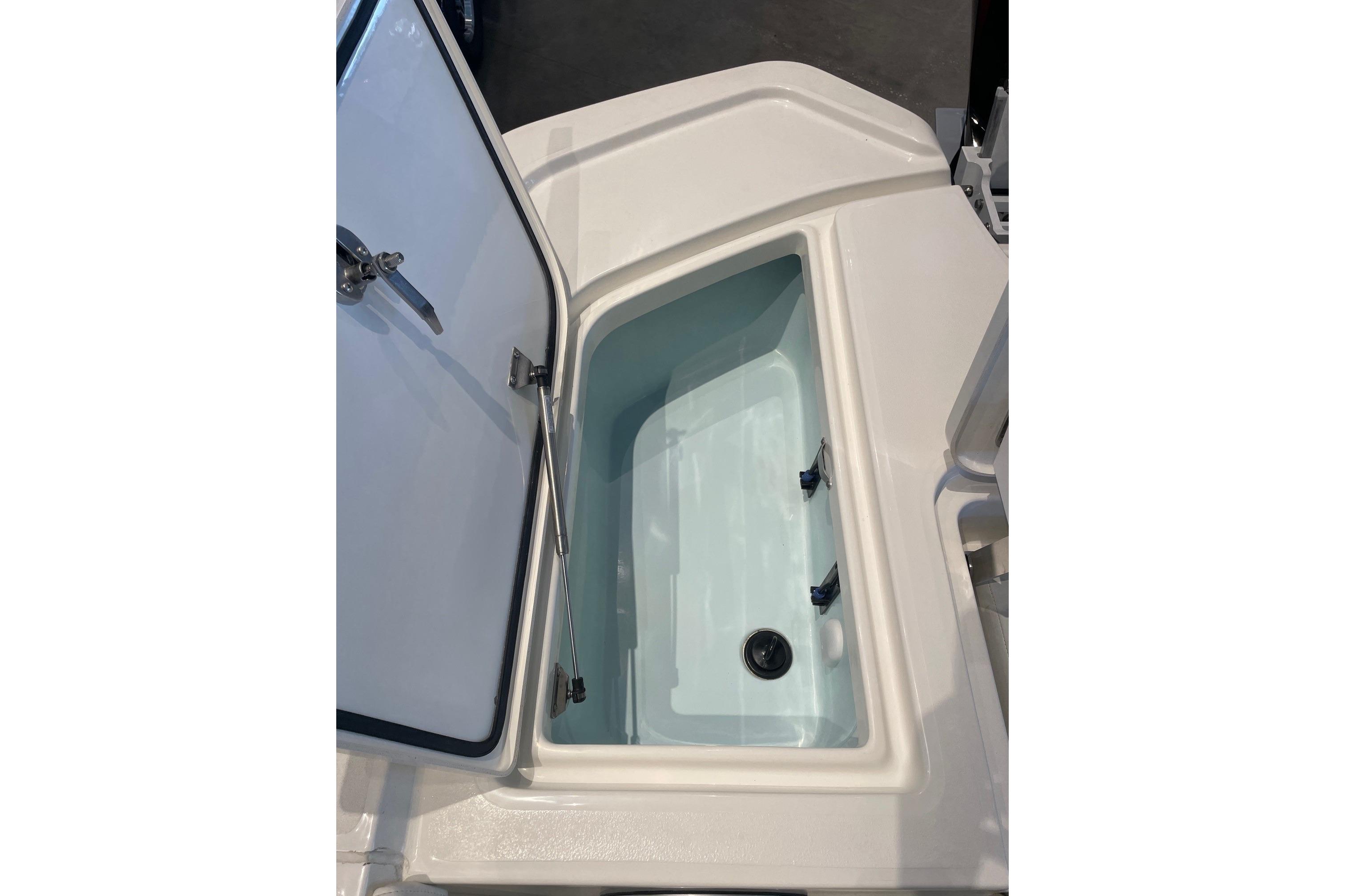 Open storage compartment on 2026 Mako 24 APEX boat, showcasing interior space.