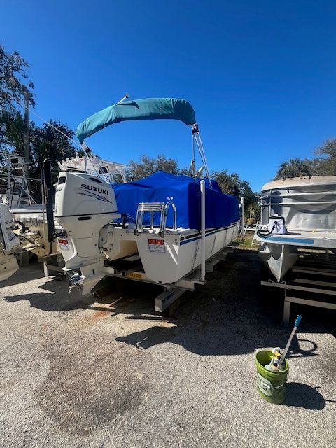 A 2017 Beachcat Catamaran with Suzuki outboard motor, parked on a trailer, covered in blue.