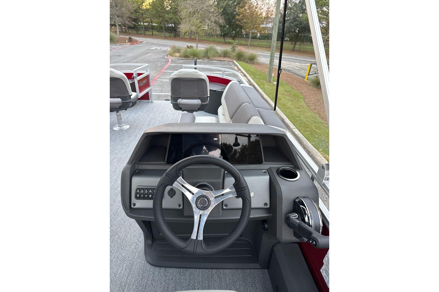 2026 Sun Tracker Fishin' Barge 22 DLX boat interior with steering wheel and seating.
