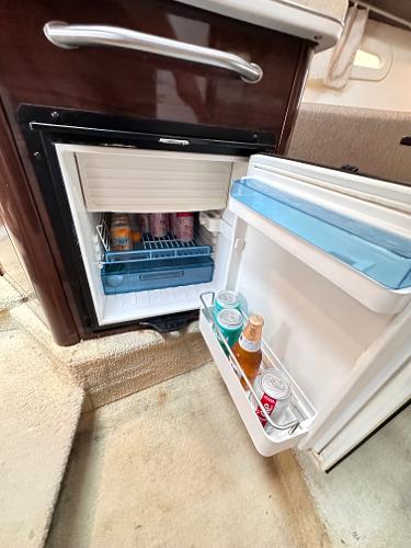 Mini fridge inside 2015 Sea Ray 260 Sundancer, stocked with beverages.