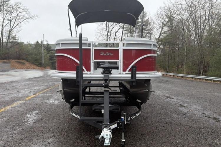 2026 Sun Tracker SportFish 22 DLX pontoon boat on trailer, parked outdoors.