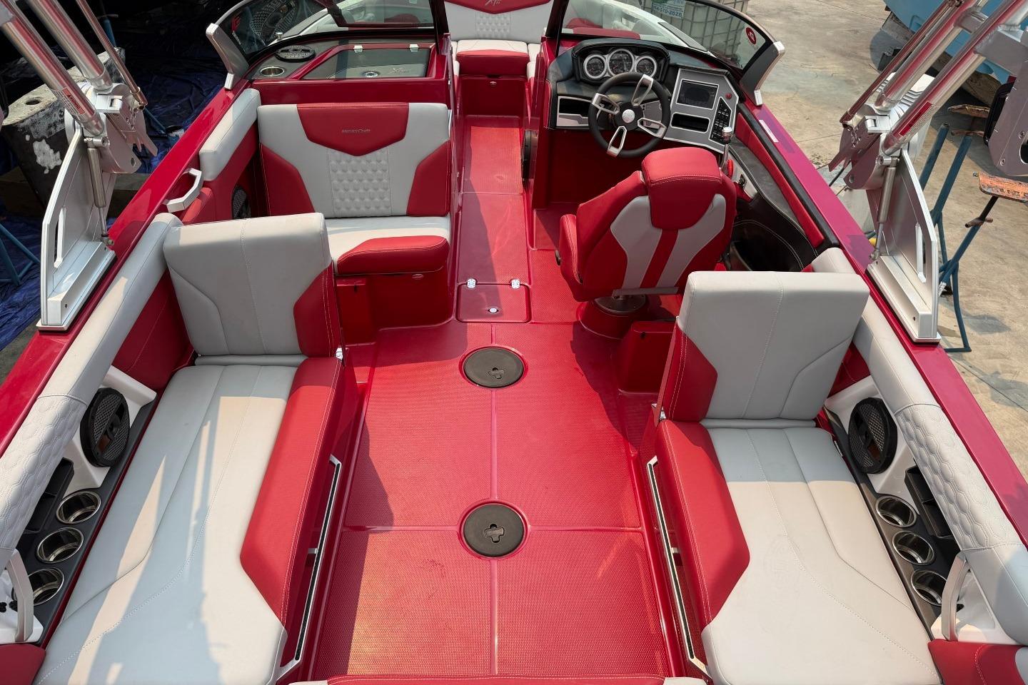 2023 MasterCraft X24 boat interior with red and white seating, modern dashboard, and spacious layout.