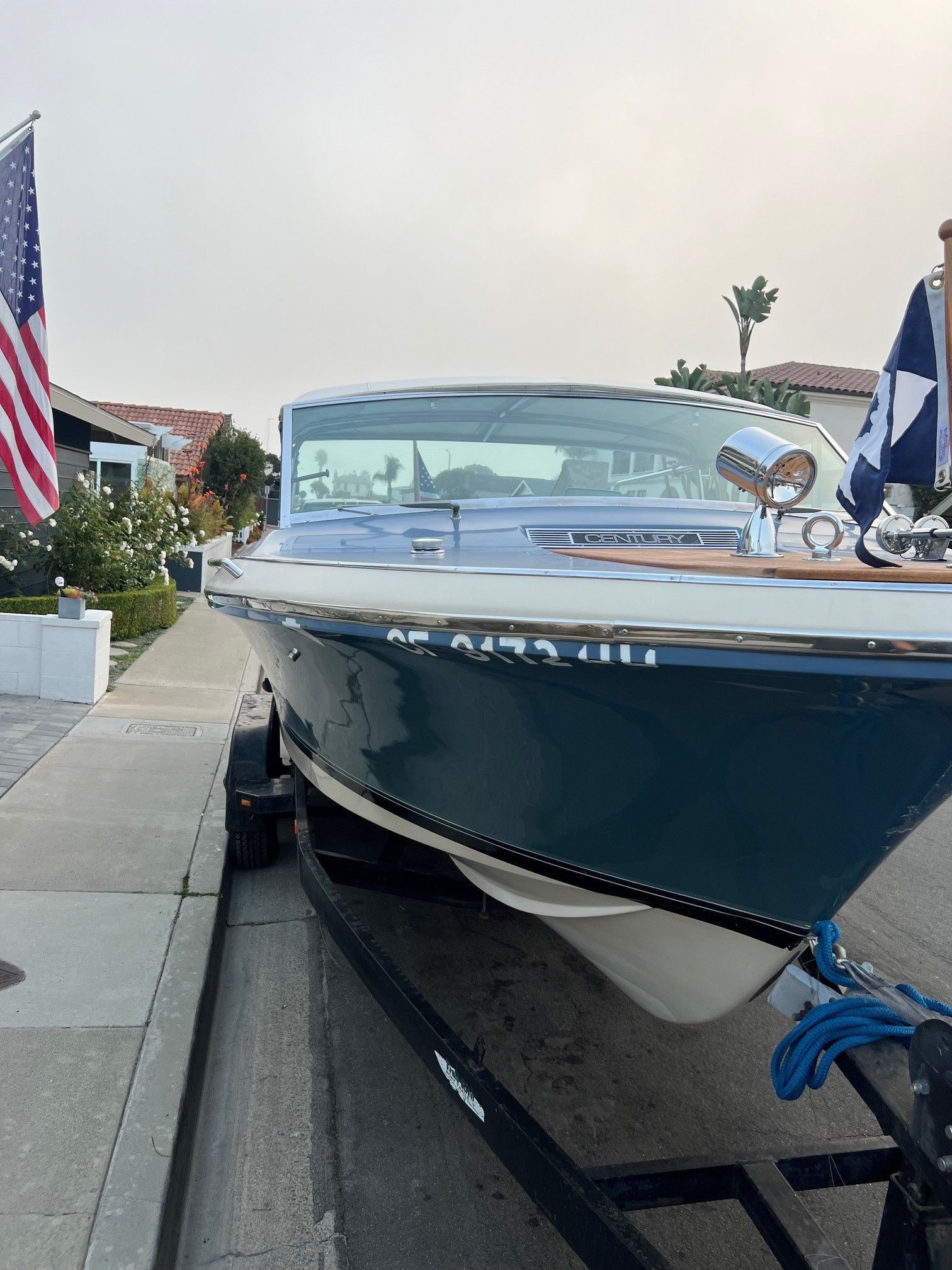 1985 Century Coronado Cardel boat on trailer, parked on residential street with American flag.